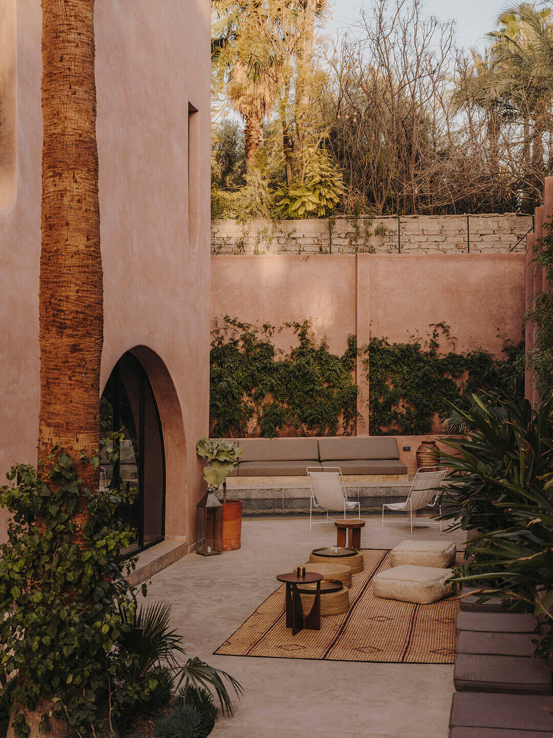 Maison Brummell Majorelle, Africa — Terracotta courtyard with arched doorway, palm trees, modern seating, and high walls creating intimate outdoor lounge space.