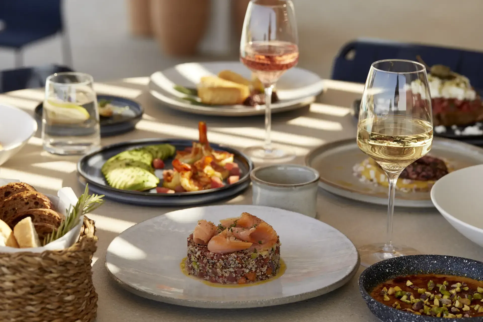 Pārocks, Europe — Fine dining table with seared tuna tartare, grilled vegetables, white wine, natural light, minimalist plating and contemporary table setting.