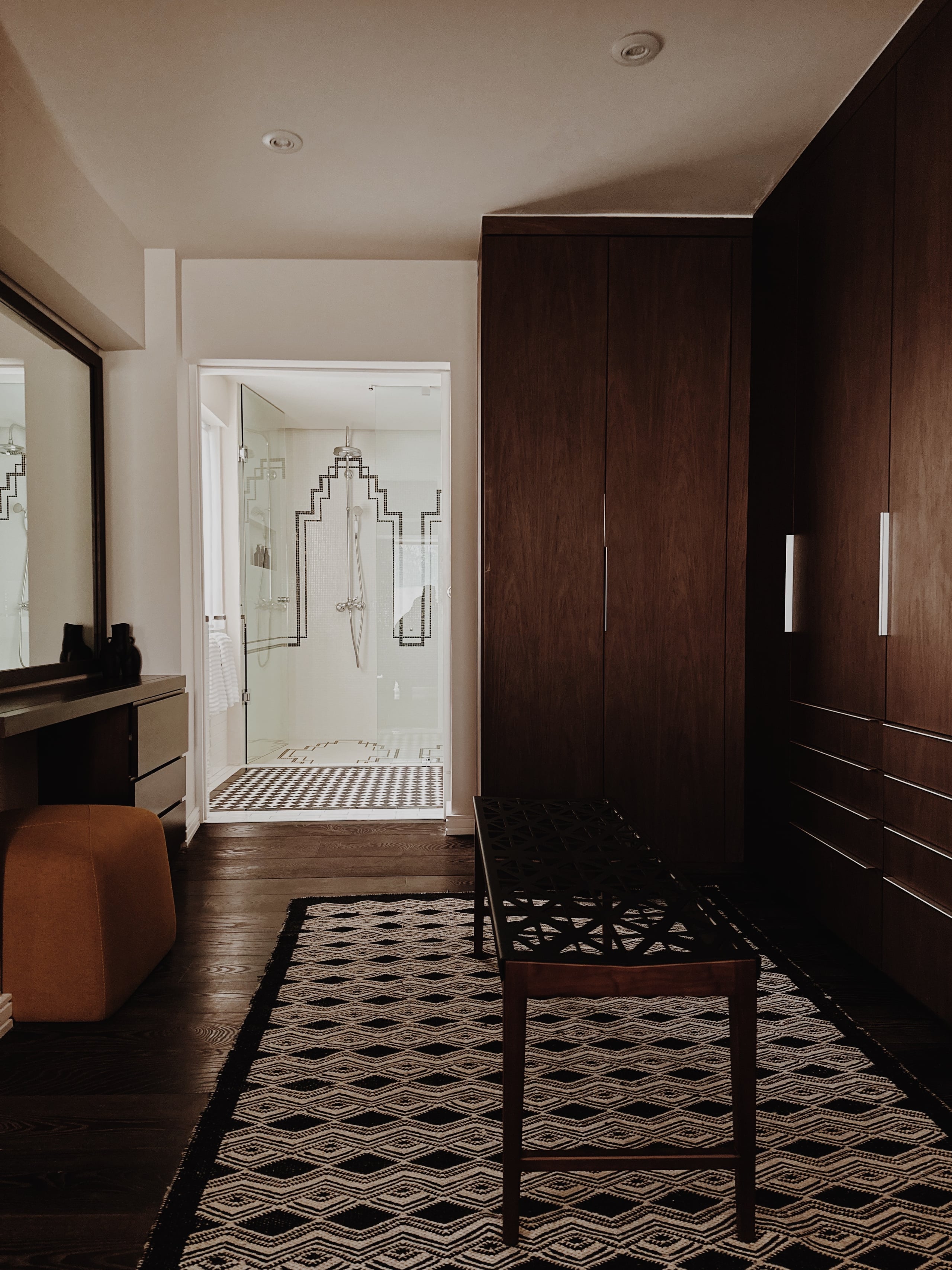 Campos Polanco, Mexico — Master bedroom suite with dark wood cabinetry, geometric patterned rug, and ensuite bathroom with geometric tile shower surround.