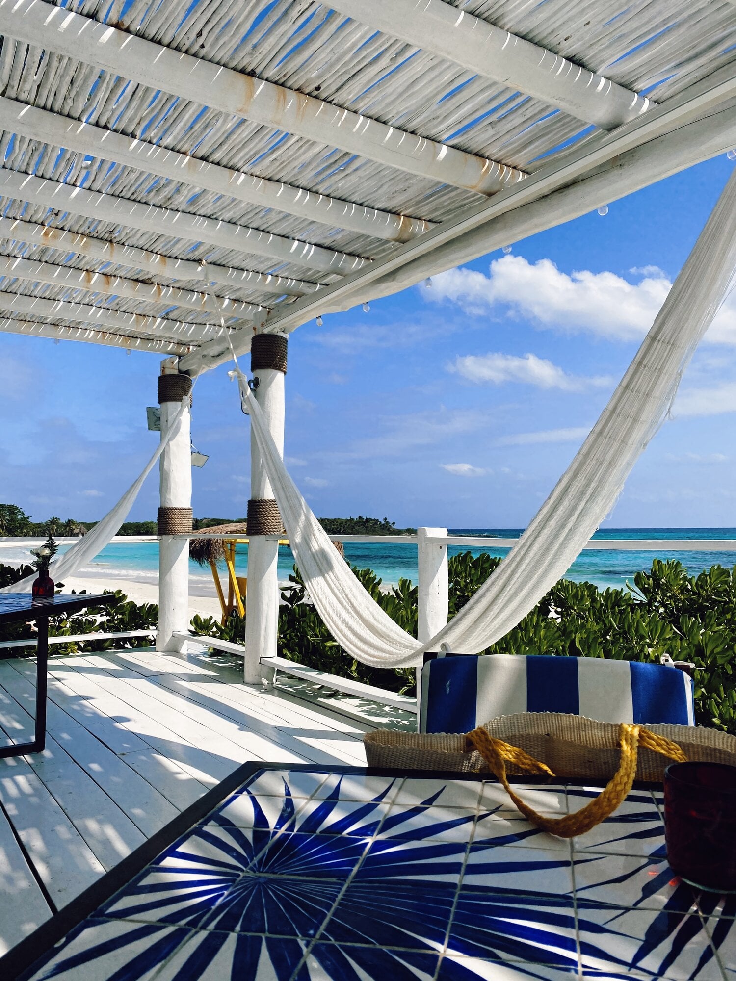 Hotel Esencia, Mexico — White pergola with billowing linen curtains frames turquoise ocean view, rope details and striped lounger below.