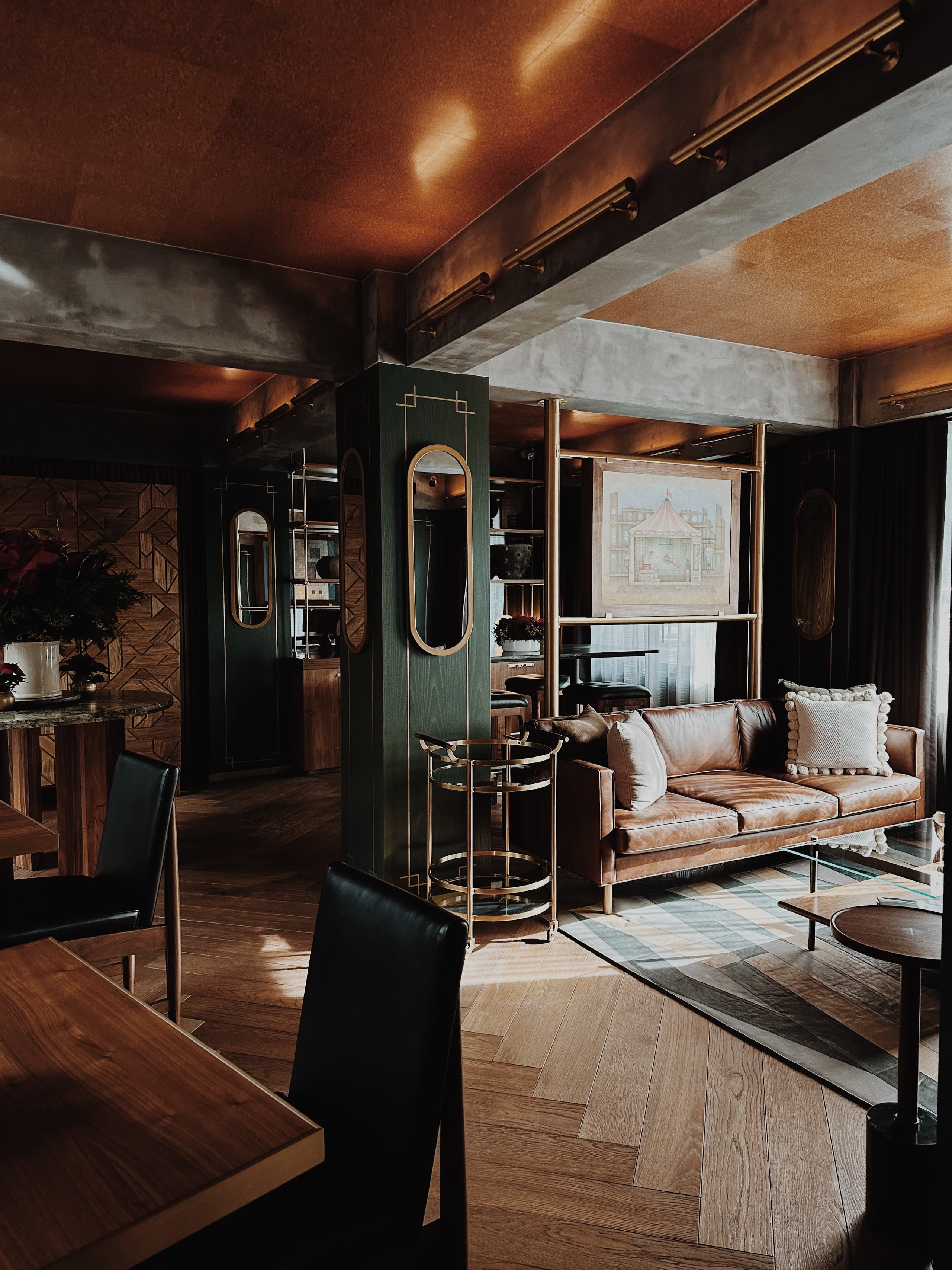 Campos Polanco, Mexico — Luxury living room with cognac leather sofa, dark wood paneling, copper ceiling, and modernist furnishings in warm ambient lighting.