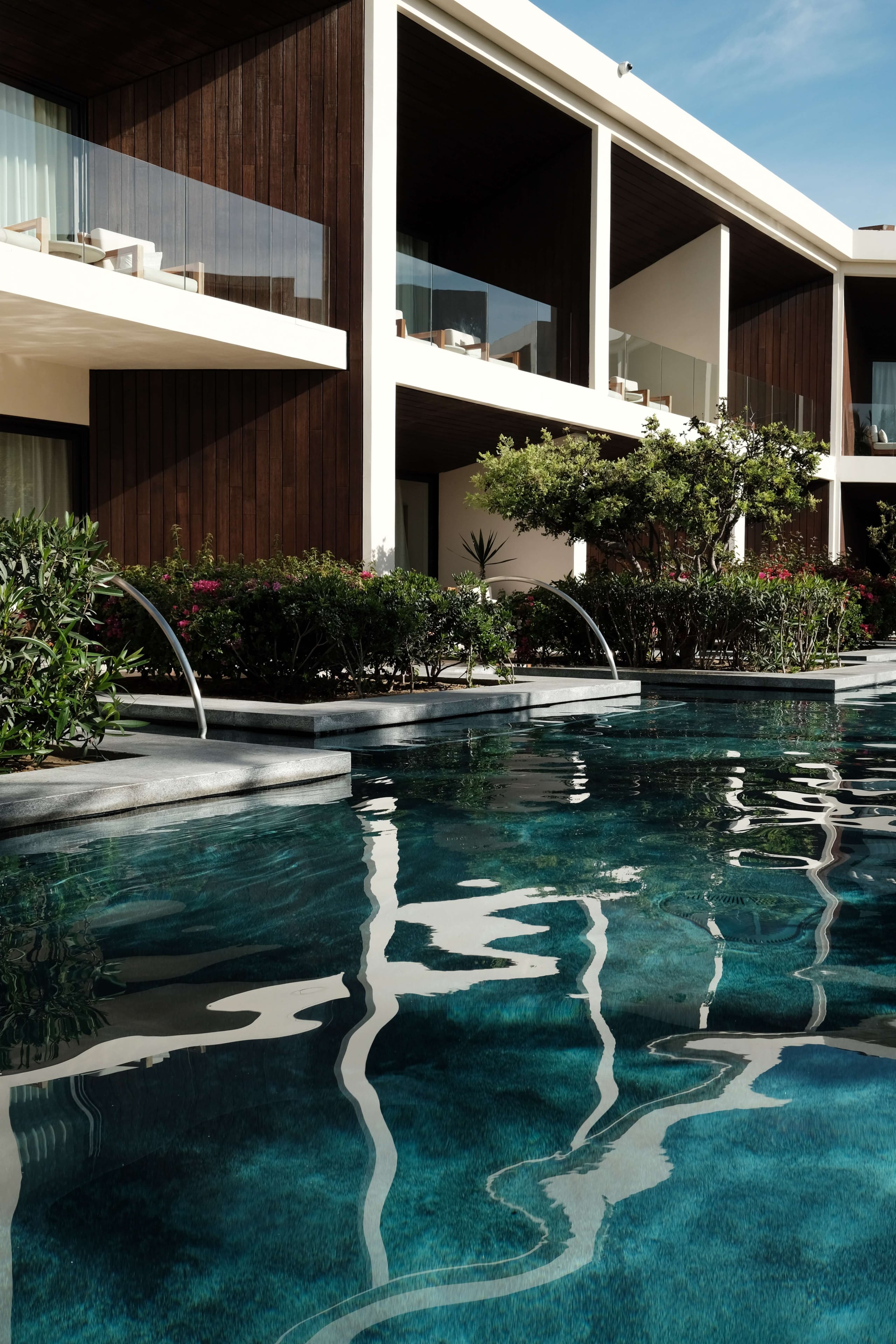 Nobu Los Cabos, Mexico — Contemporary oceanfront villa with dark wood and white concrete architecture, turquoise infinity pool reflecting modernist design and desert landscaping.