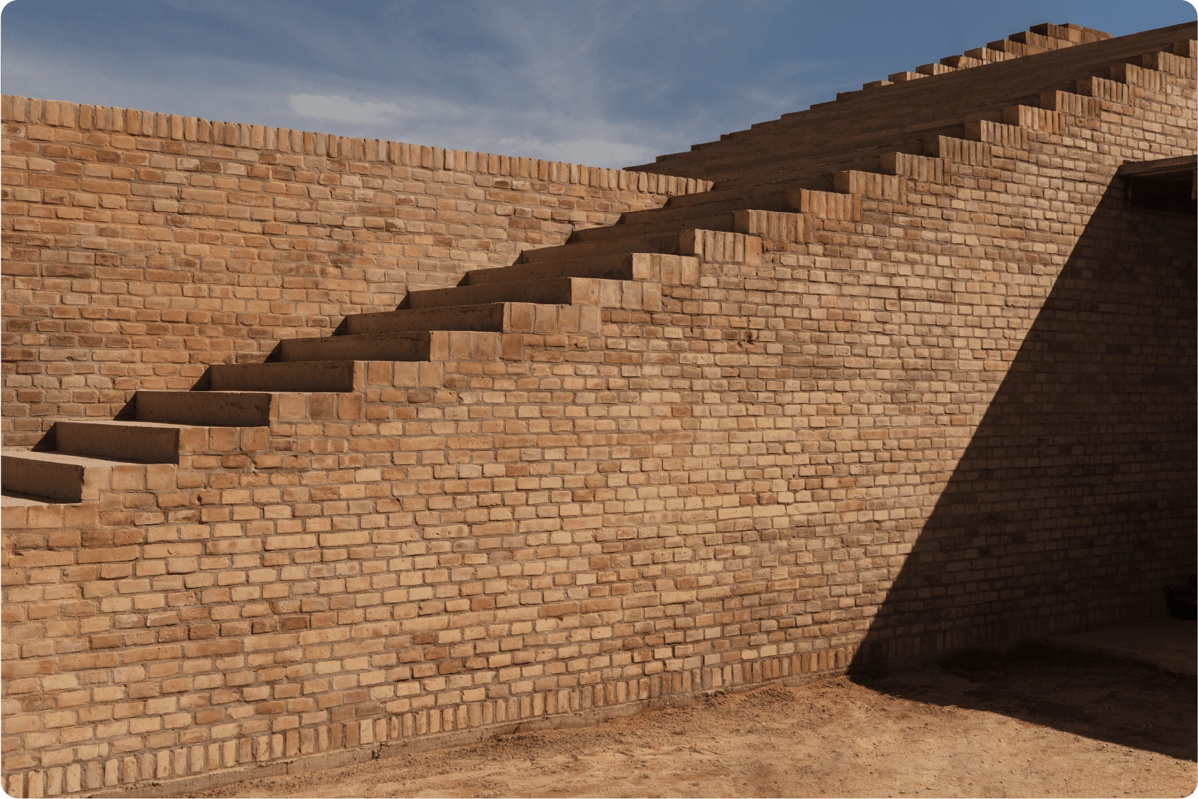 Hotel Terrestre, Mexico — Geometric brick architecture with stepped cutouts casting sharp shadows, warm terracotta walls meeting pale sky in minimalist design.