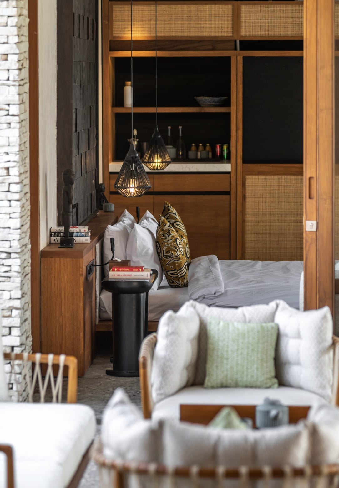 Cap Karoso, Asia — Modern bedroom with warm wood cabinetry, rattan panels, geometric pendant lights, marble accents, and curated hospitality design.