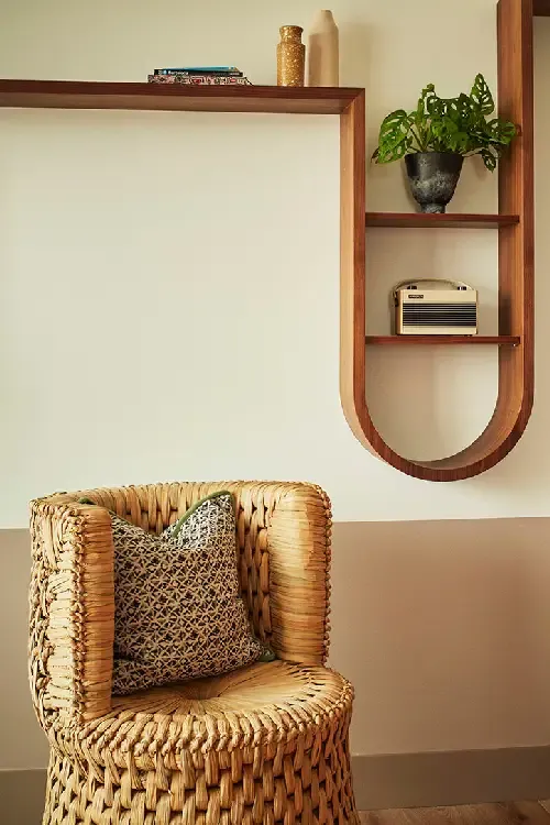 The Hoxton Poblenou, Barcelona, Spain — Woven rattan chair with textured pillow beside wooden shelving unit displaying potted plant and vintage radio.