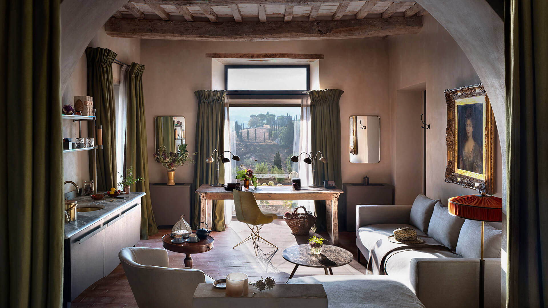 Castello di Reschio, Umbria, Italy — Tuscan villa suite with exposed beams, sage curtains, countryside views, marble desk, linen seating, and ochre plaster walls.