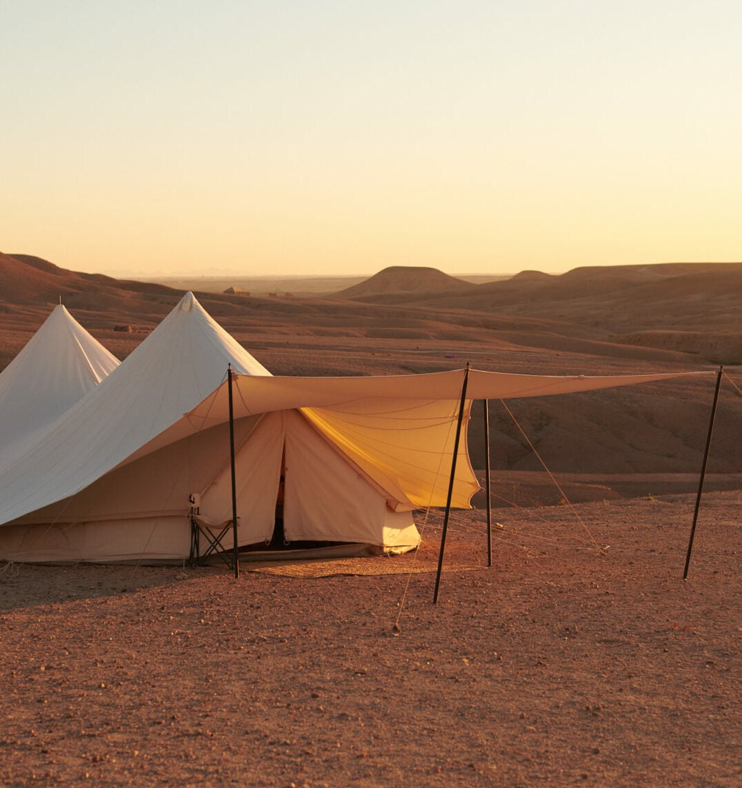 Scarabeo Camp, Africa — Canvas glamping tents with golden hour lighting in desert landscape, warm earth tones and minimalist luxury accommodation.