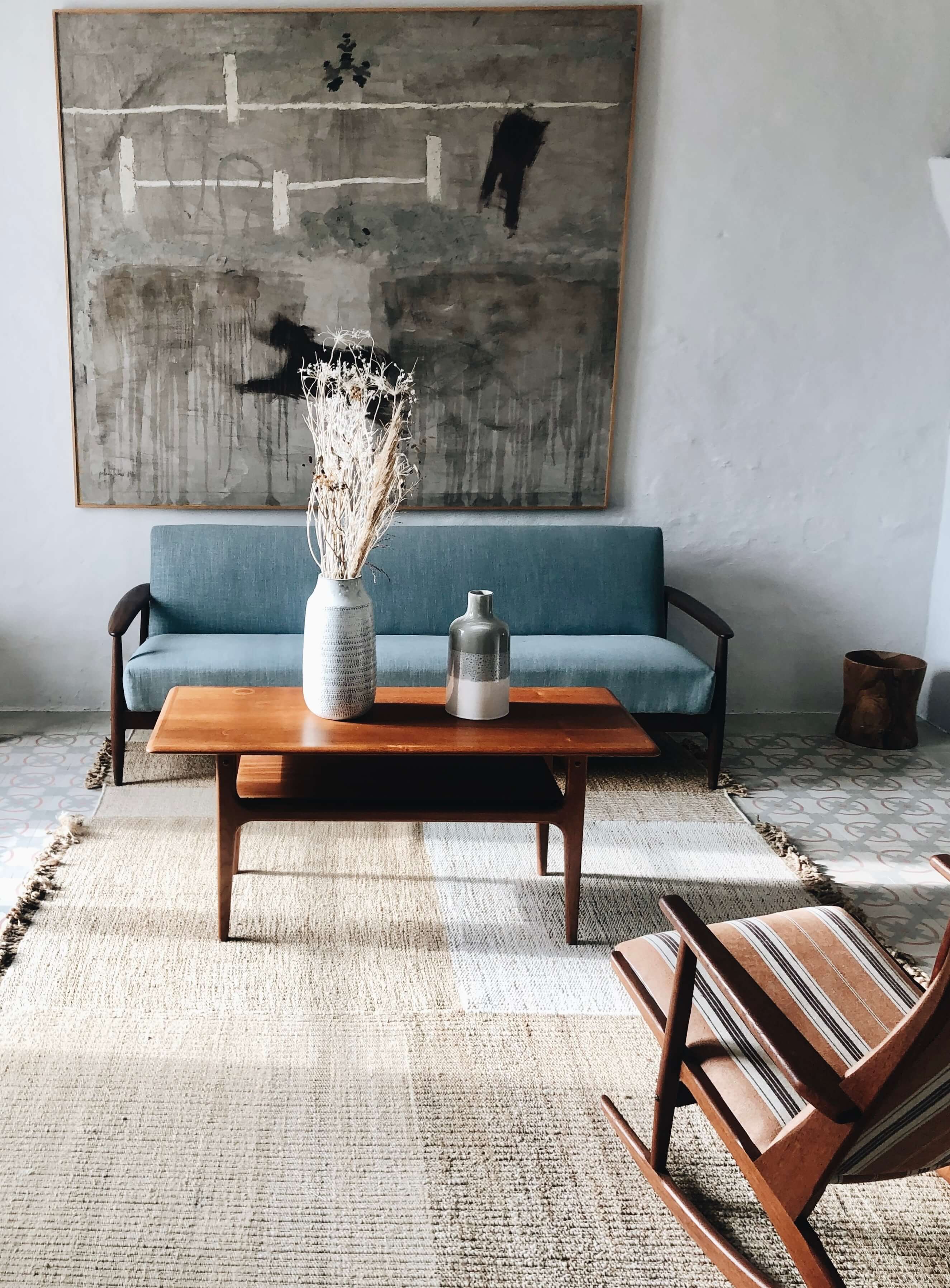 Es Bec d’Aguila — Es Bec d'Aguila, Balearic Islands, Spain — Mid-century modern living room with teal sofa, wooden coffee table, striped chairs, neutral textiles, and abstract artwork.