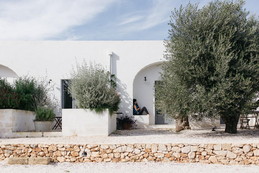 Masseria Moroseta, Europe — Whitewashed stone villa with curved architecture, olive trees, and rustic dry-stone wall in Mediterranean landscape.