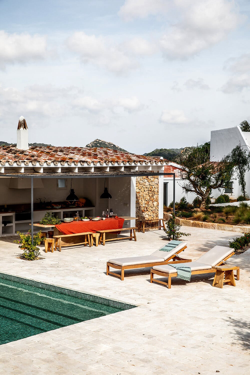 Es Bec d’Aguila — Es Bec d'Aguila, Balearic Islands, Spain — Terracotta-roofed villa with poolside dining pavilion, teak loungers, and stone-walled courtyard overlooking forested hills.