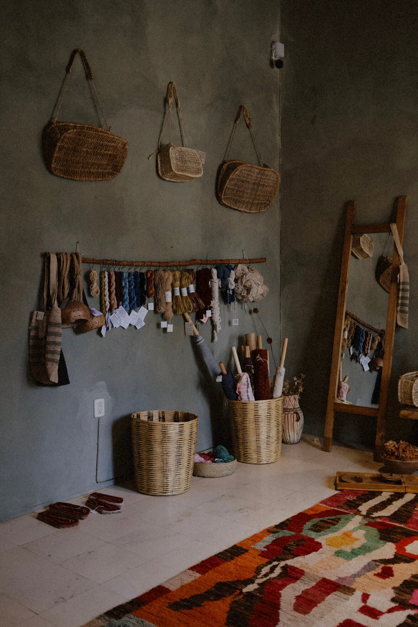 Texere, Mexico — Artisan weaving studio with woven baskets, dyed yarn samples, wooden looms, and traditional textiles displaying natural fibers and earthy tones.