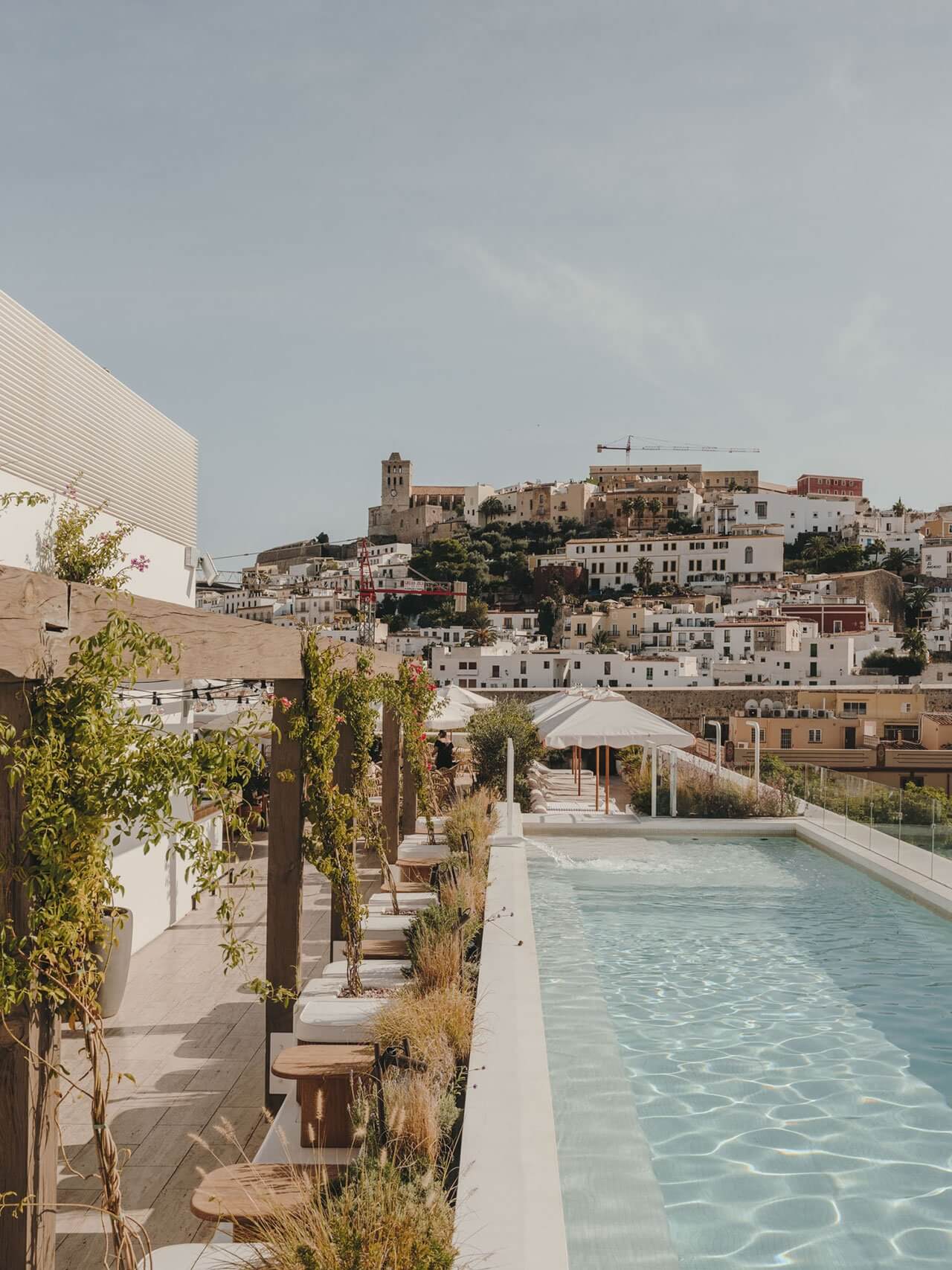 The Standard Ibiza, Balearic Islands, Spain — Rooftop pool with turquoise water overlooking whitewashed old town architecture and hilltop castle at sunset.