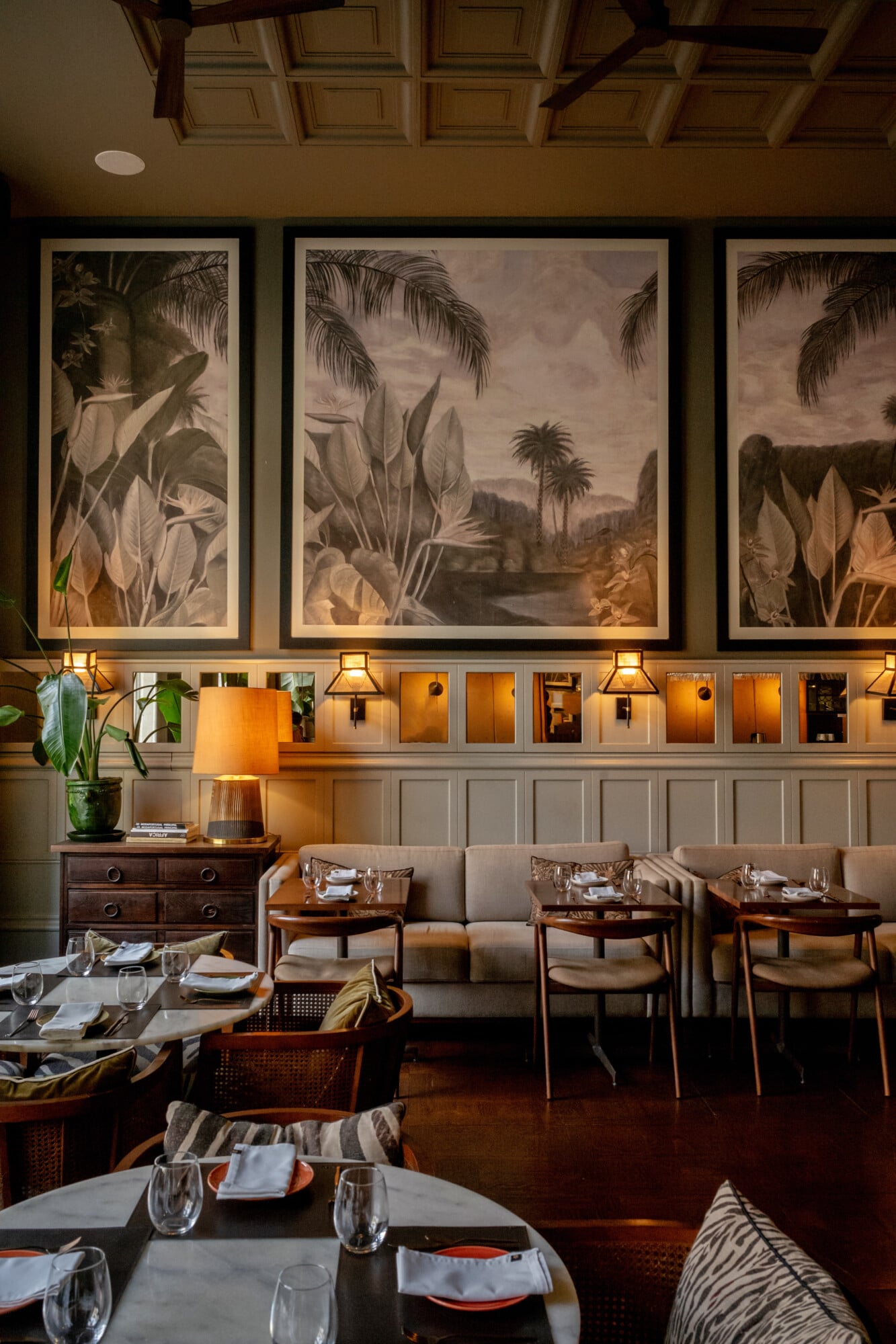 Torel 1884, Porto, Portugal — Botanical framed artwork above paneled wall with warm lamplight, mid-century dining chairs, coffered ceiling, luxury hospitality interior.