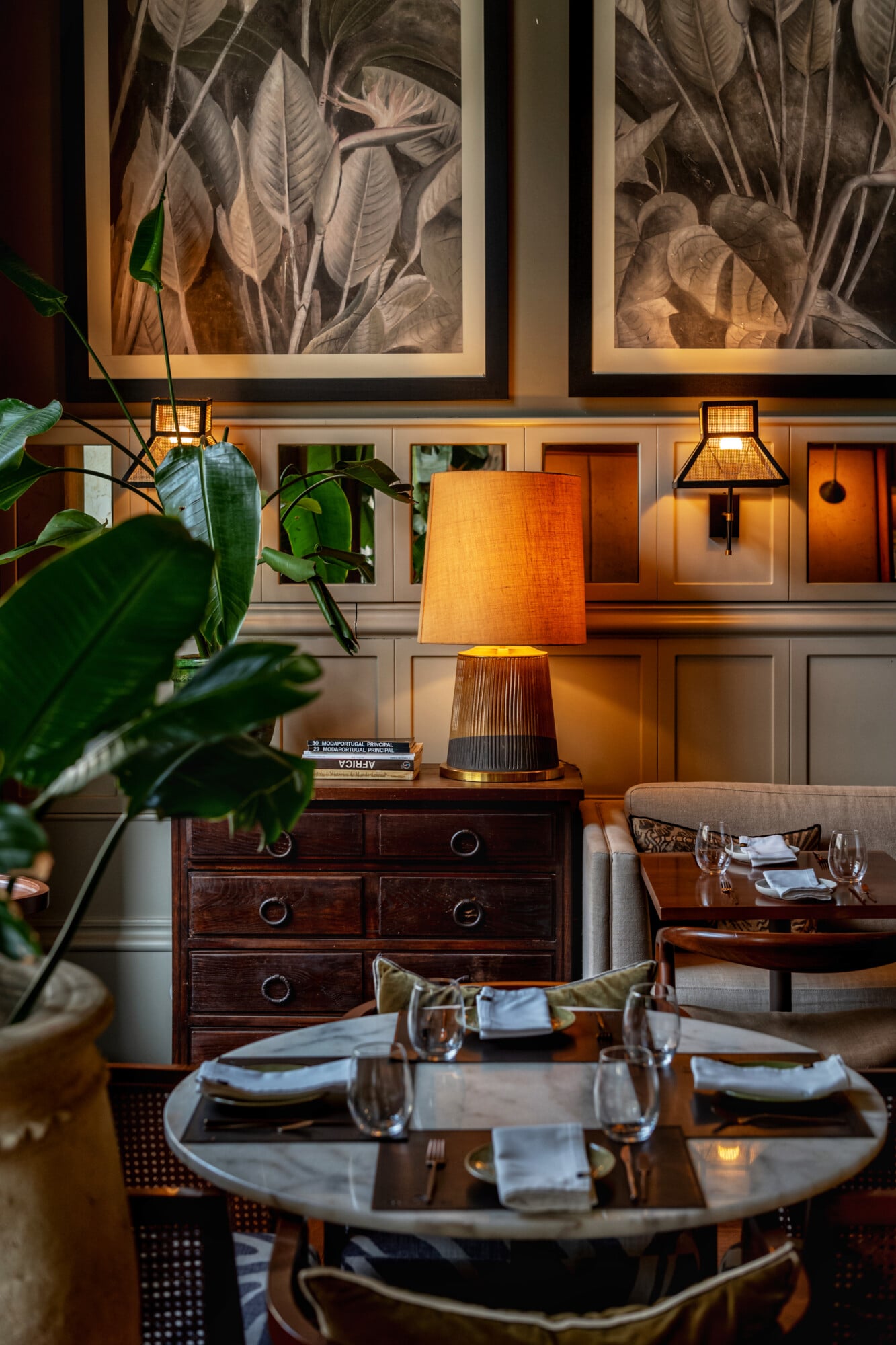 Torel 1884, Portugal — Dining room with marble table, dark wood chest, linen lampshade, botanical artwork, and warm ambient lighting.
