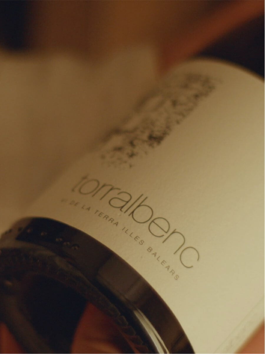 Torralbenc, Balearic Islands, Spain — Wine bottle detail with cream label against warm ambient lighting, luxury hospitality branding.