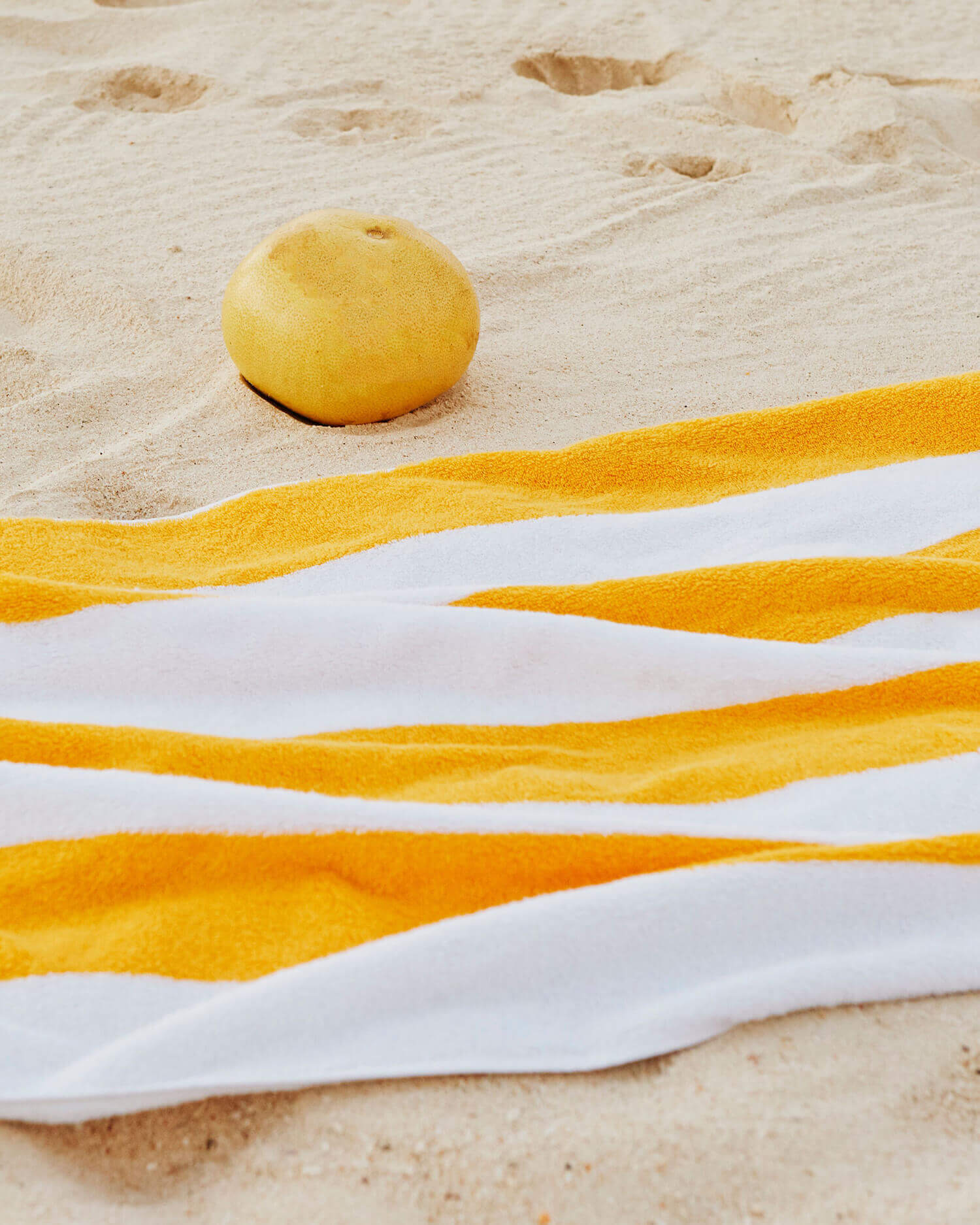 Palm Heights, North America — Yellow ribbon and citrus fruit arranged on sand, minimalist beach styling with white linen and natural light.