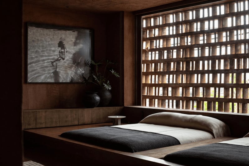 Further Hotel, Asia — Minimalist bedroom with dark wood platform bed, geometric latticed window, black and white photography, warm natural light, luxury modern design.
