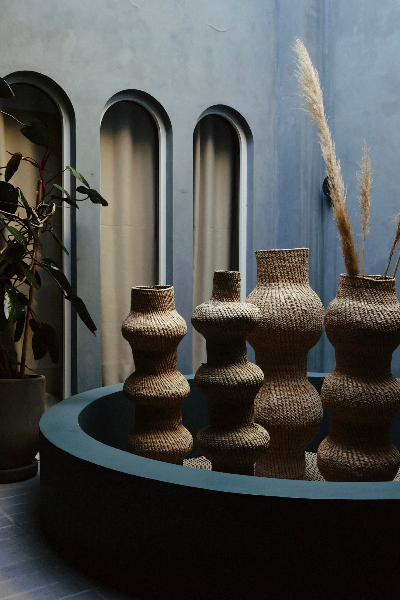 UMA Casa, Mexico — Woven vessels arranged on curved plinth against arched alcoves, pampas grass, minimalist hospitality design.