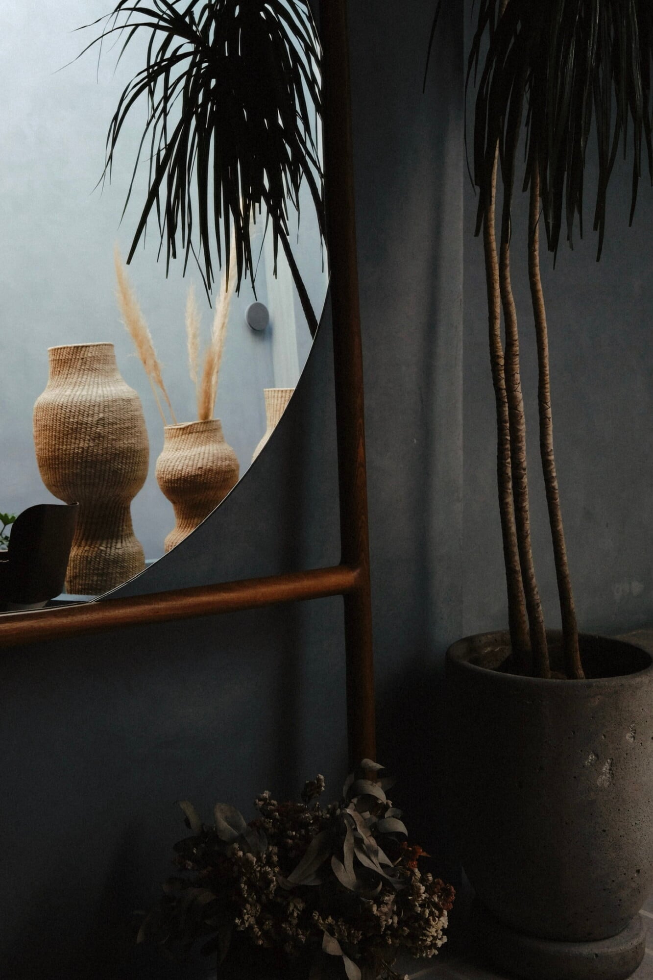 UMA Casa, Mexico — Woven baskets with dried grasses beside concrete planter with trailing black foliage, wooden railing, minimalist interior styling.
