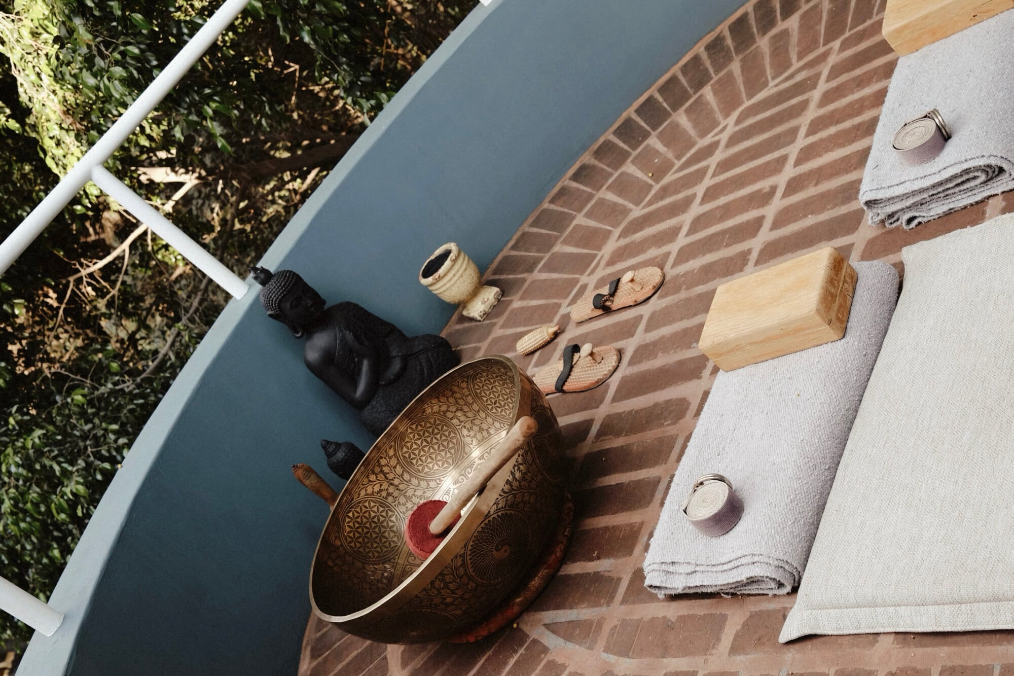 UMA Casa, Mexico — Overhead view of artisan spa amenities including ornate brass bowl, linen towels, wooden brushes, and natural materials on terracotta brick floor.