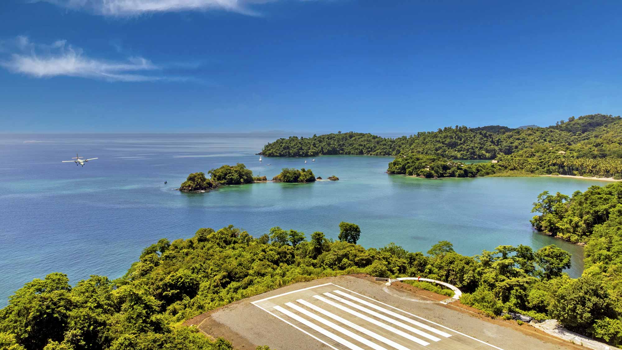 Islas Secas, Panama — Seaplane approaching landing strip overlooking emerald lagoon, forested islands, and turquoise waters beneath clear sky.