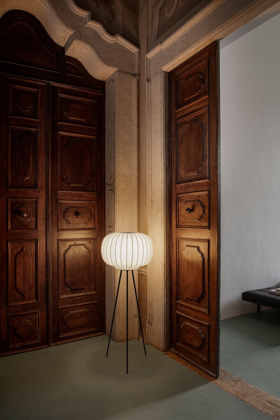 Vipp Palazzo Monti, Italy — Modernist pendant lamp with ribbed white shade beside ornate wooden doors in historic palazzo foyer, warm ambient light.