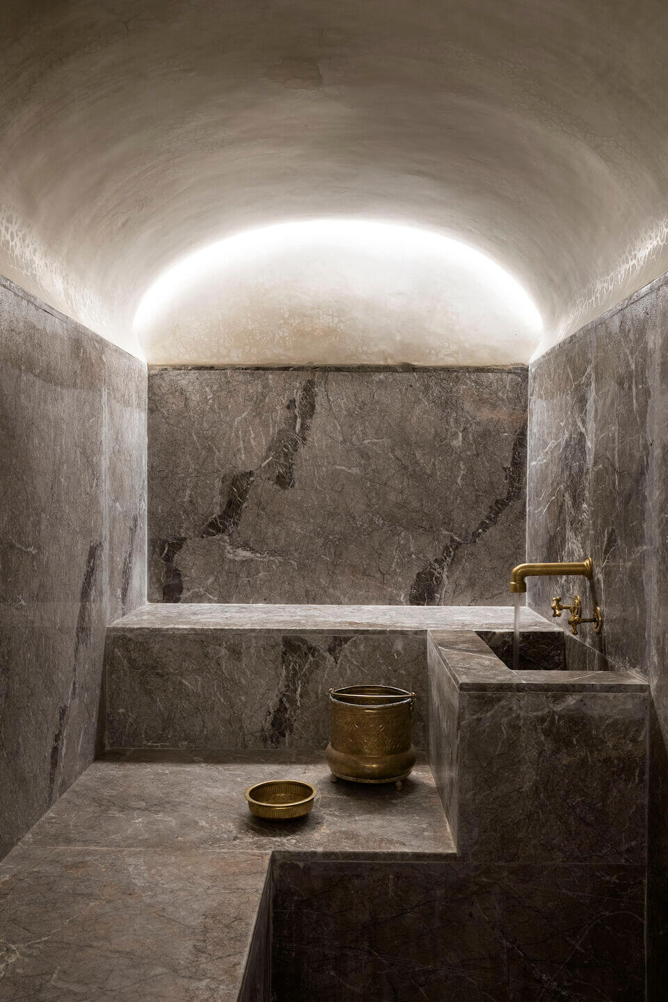 Maison Brummell Majorelle, Africa — Minimalist stone bathroom with barrel-vaulted ceiling, brass fixtures, and diffused skylight creating serene spa-like ambiance.
