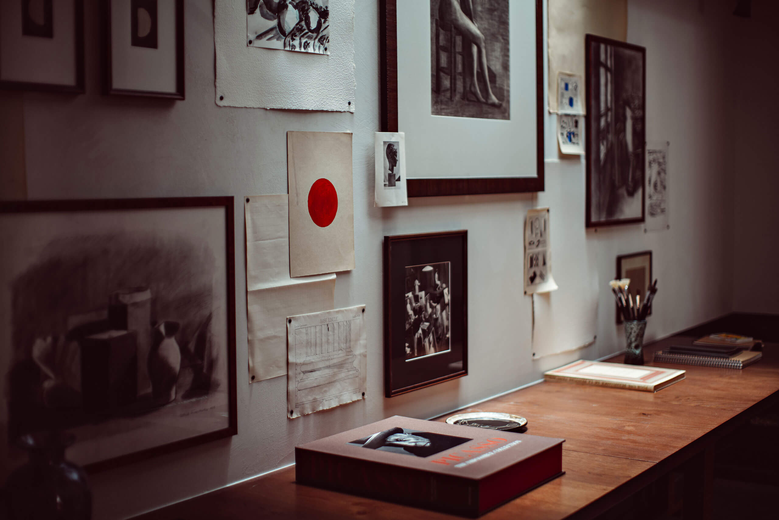 Académies et des Arts, Europe — Gallery exhibition space with framed photographs, architectural drawings, and red accent details on white walls, wooden flooring, natural light.