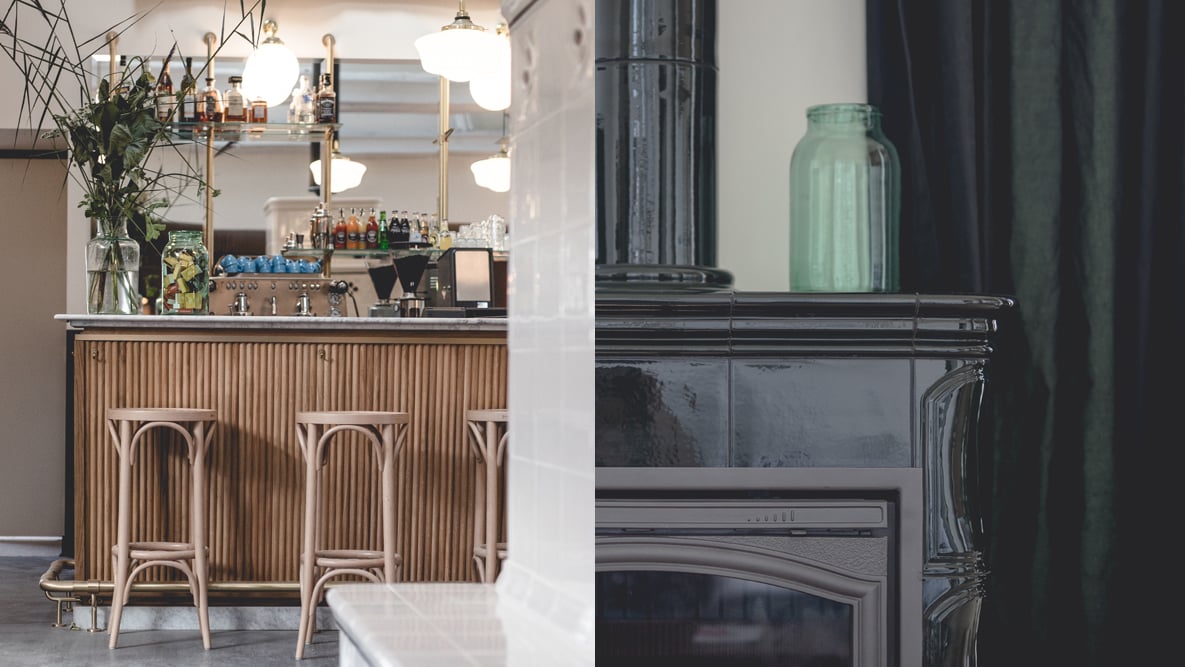 Le Barn Bar, Europe — Wooden bar counter with curved art deco paneling, brass pendant lights, and fireplace with green glass bottle, modern hospitality interior.