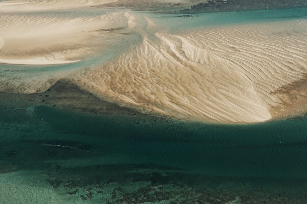 Dhow Safari, Africa — Aerial view of turquoise lagoon with rippled sand banks and shallow waters, tropical coastal landscape.
