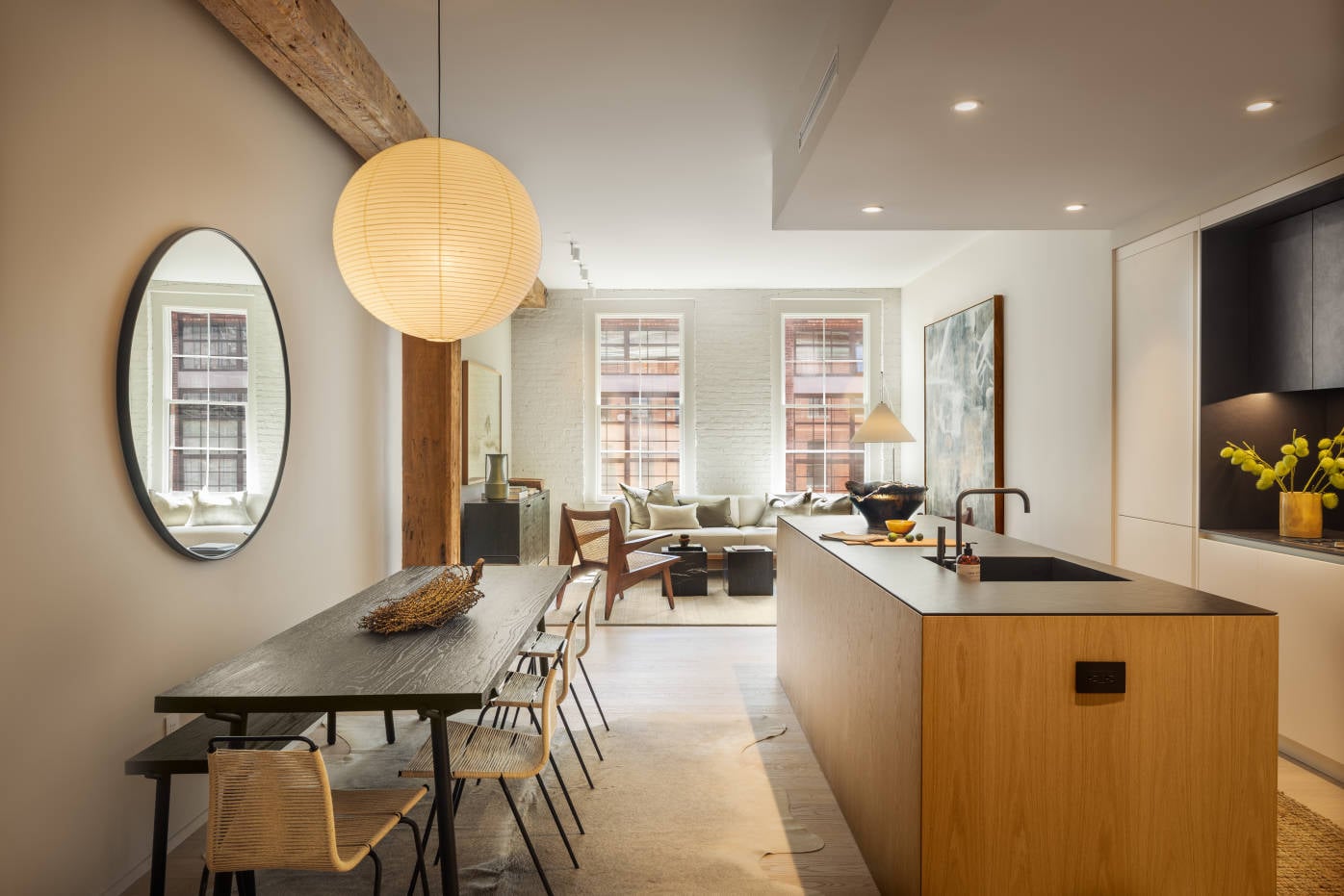 168 Plymouth, North America — Modern kitchen and dining area with walnut island, black dining table, pendant lighting, and living room visible through open floor plan with brick windows.