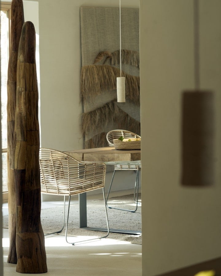 Farm to Table Restaurant, Balearic Islands — Minimalist dining space with woven rattan chair, wooden sculptural element, pendant light, and textured wall art in natural tones.