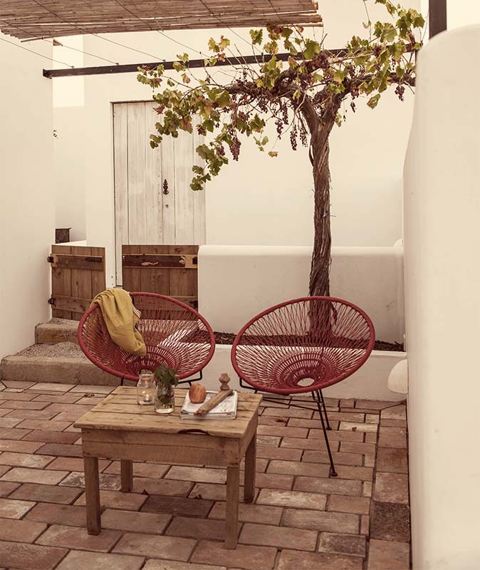 Pensão Agrícola, Europe — Terracotta courtyard with burgundy woven chairs, wooden table, grapevine, whitewashed walls, and colonial architecture.