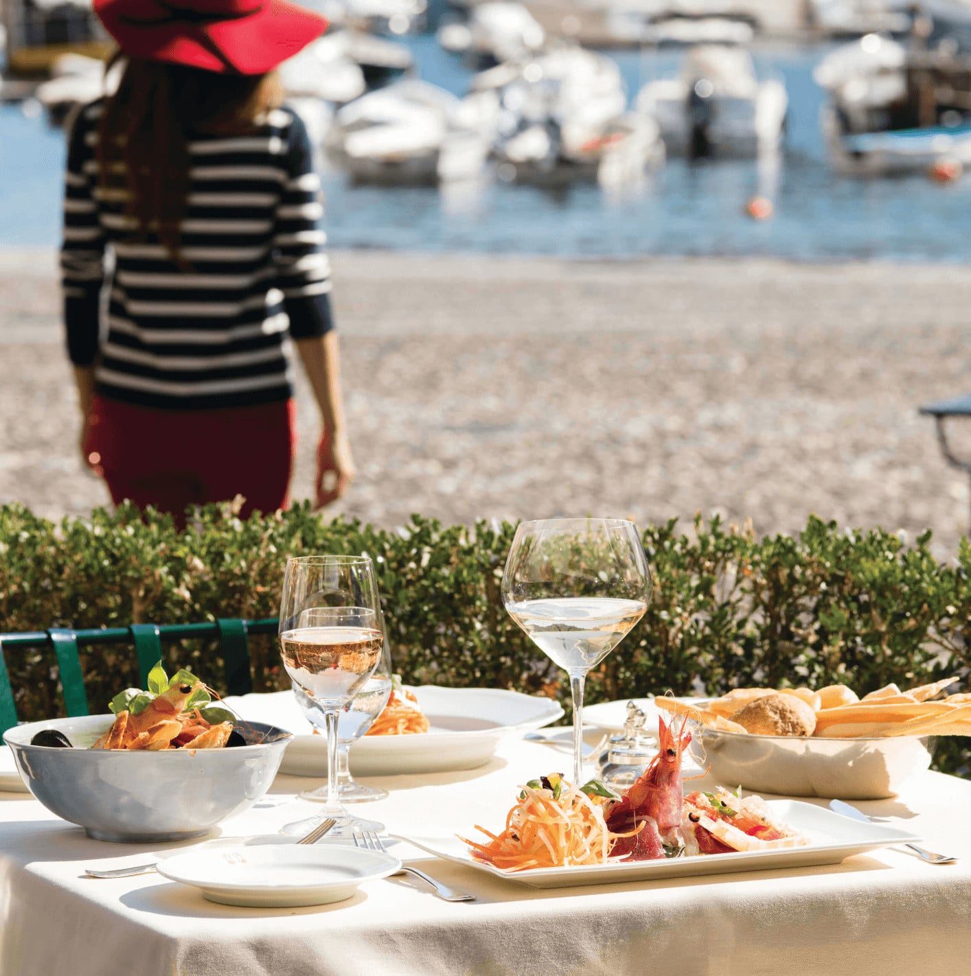 DaV Mare, Europe — Seaside dining table with grilled seafood, rosé wine, and striped linen overlooking Mediterranean harbor and moored boats.
