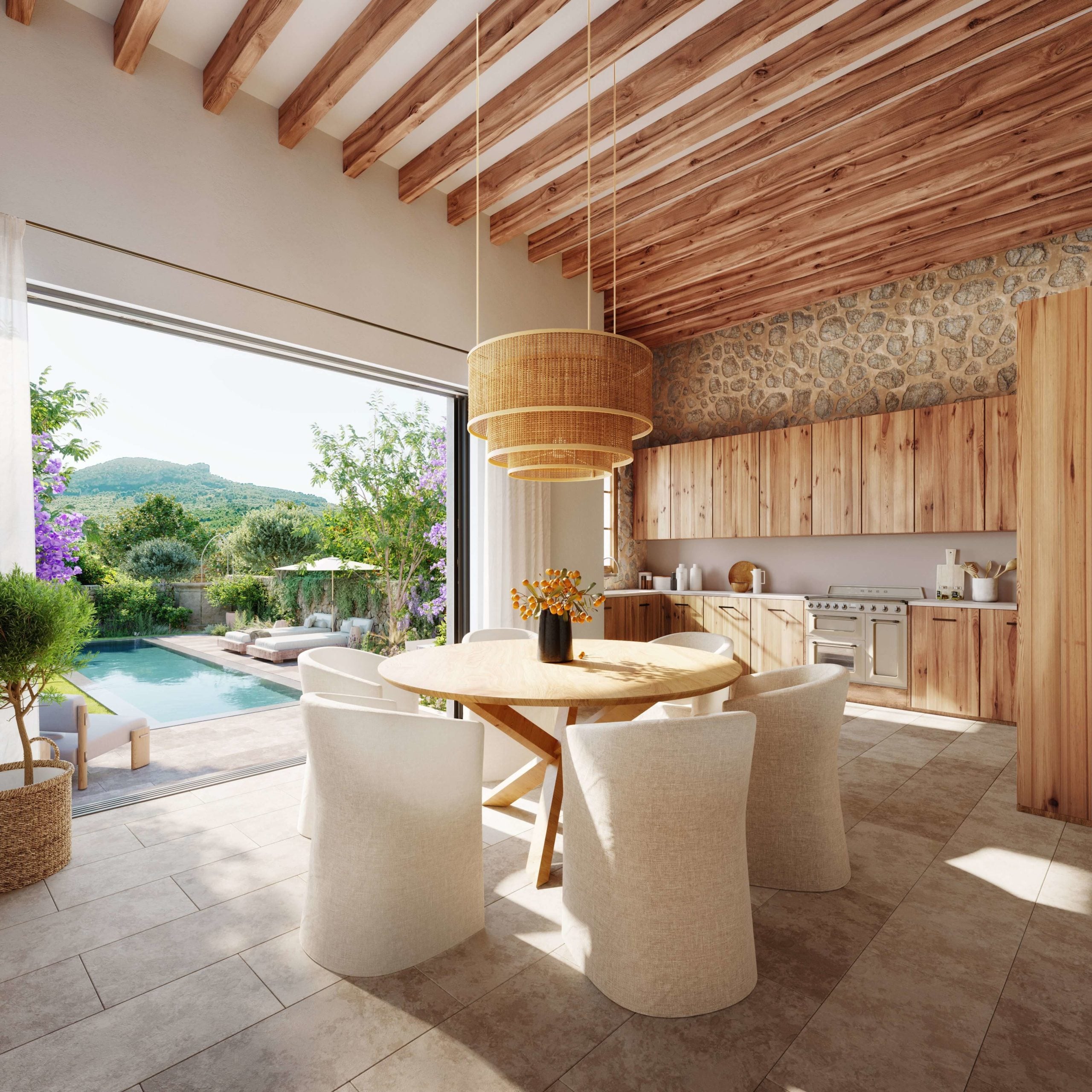Casa Mares, Balearic Islands, Spain — Open-plan kitchen and dining space with wooden beams, rattan pendant lights, and views to pool and Mediterranean landscape.