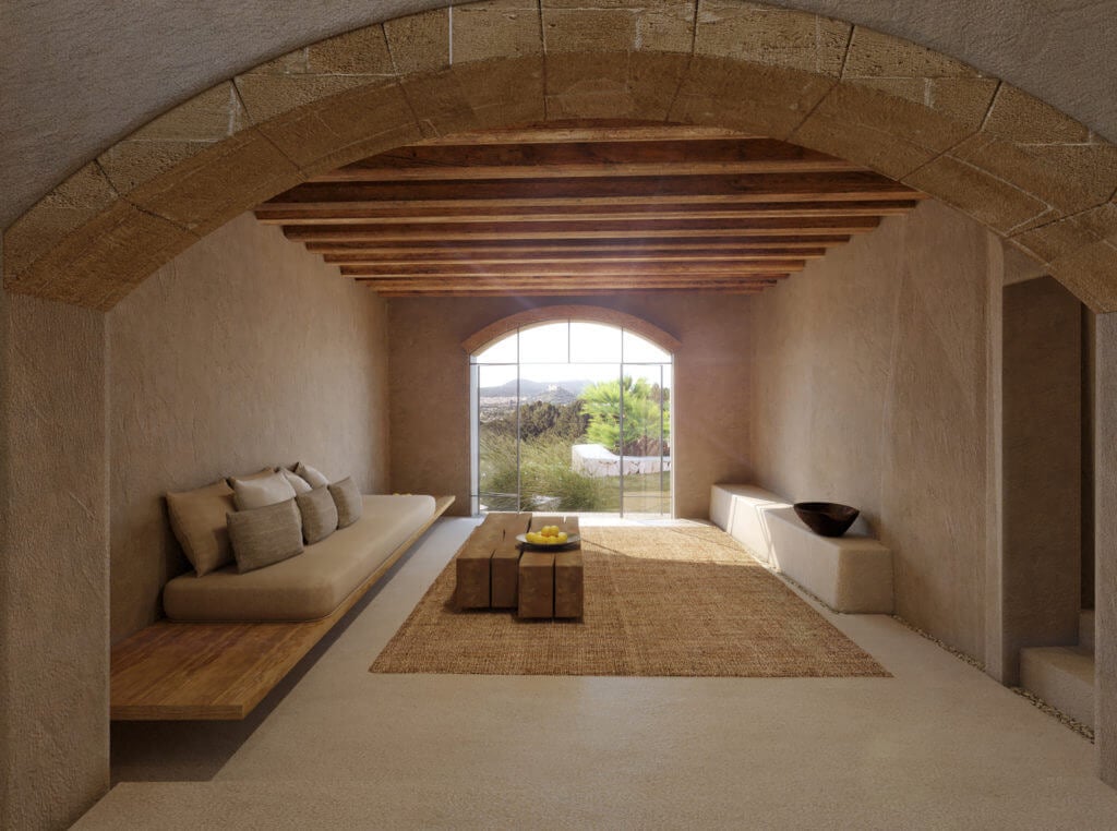 Es Racó d'Artà, Balearic Islands — Arched stone room with wooden ceiling beams, built-in seating, natural light from large window, Mediterranean minimalist interior design.