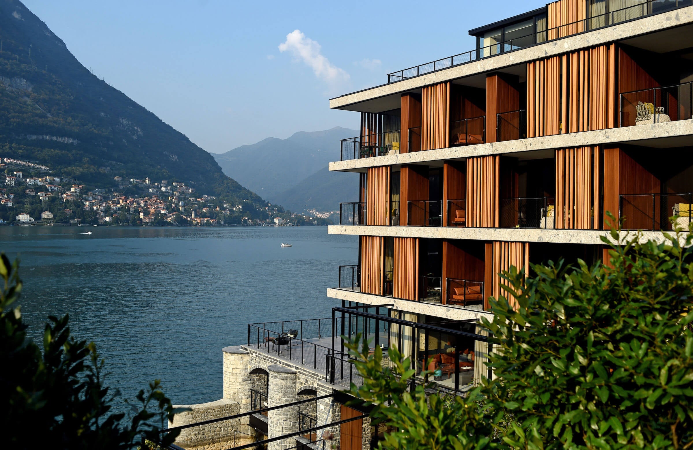 il Sereno Lago di Como, Lake Como, Italy — Modern waterfront hotel with timber-clad facades, concrete balconies, and alpine mountain views across turquoise water.