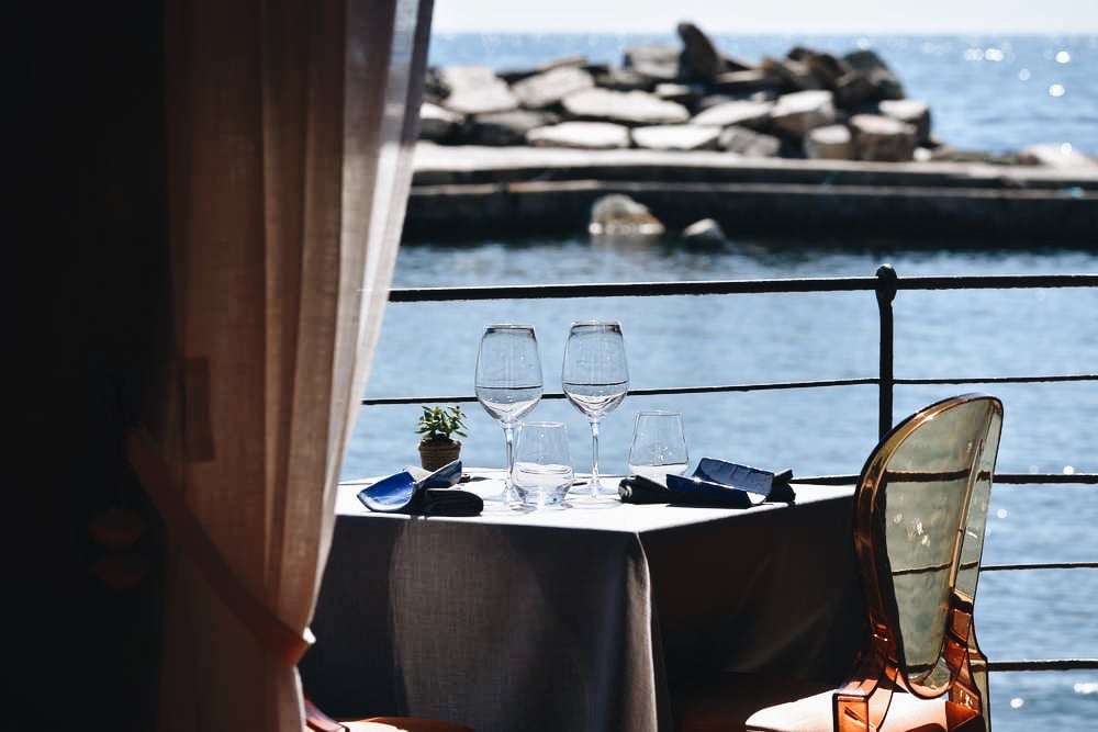 Restaurant le Pirate, Europe — Waterfront dining table with empty wine glasses, dark tablecloth, and sea view overlooking breakwater with sunbathing seals.