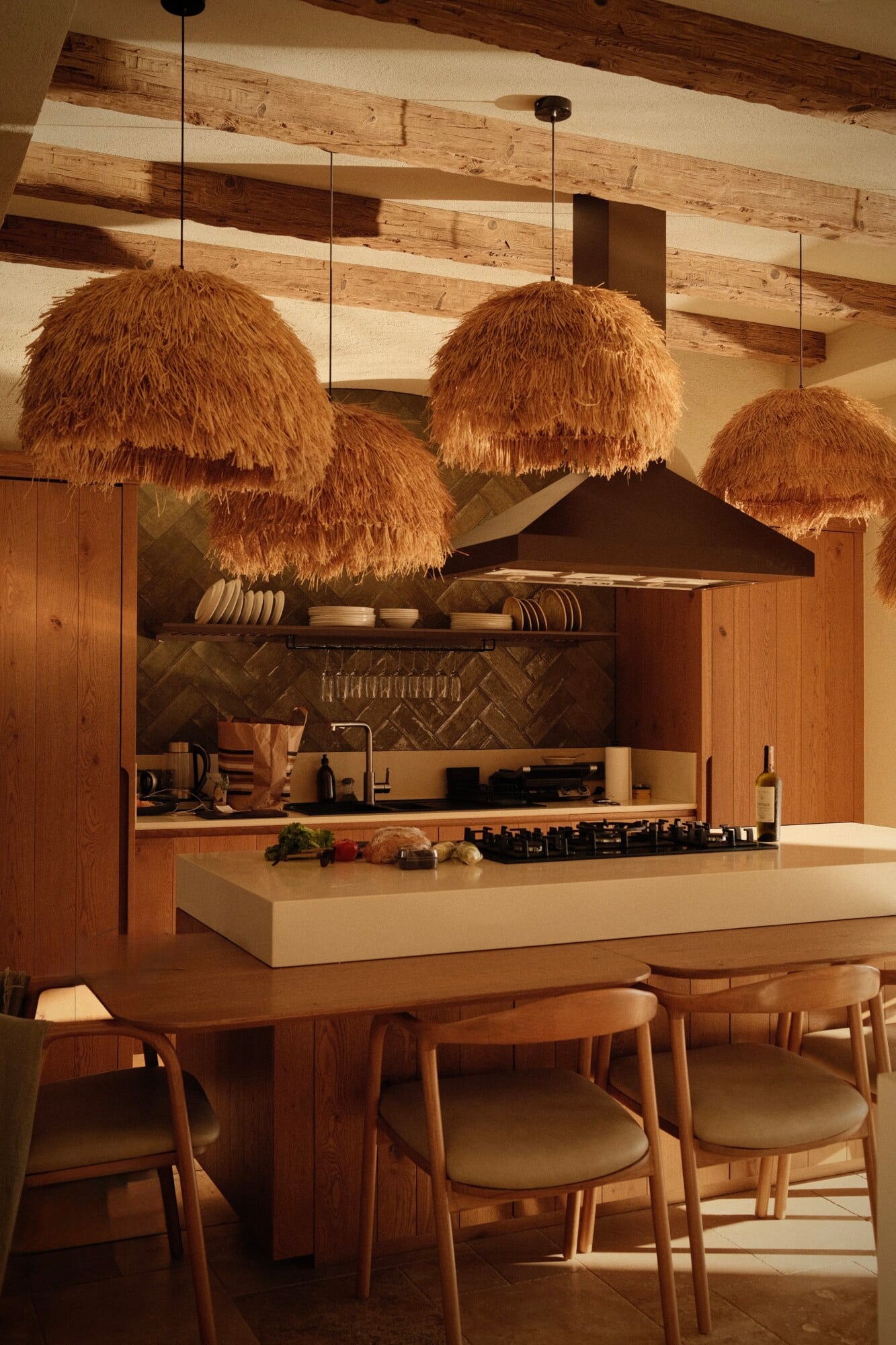 Villa Thalia by Muses Kalkan, Asia — Modern kitchen with woven pendant lights, timber beams, herringbone backsplash, cream island, and mid-century dining chairs in natural light.