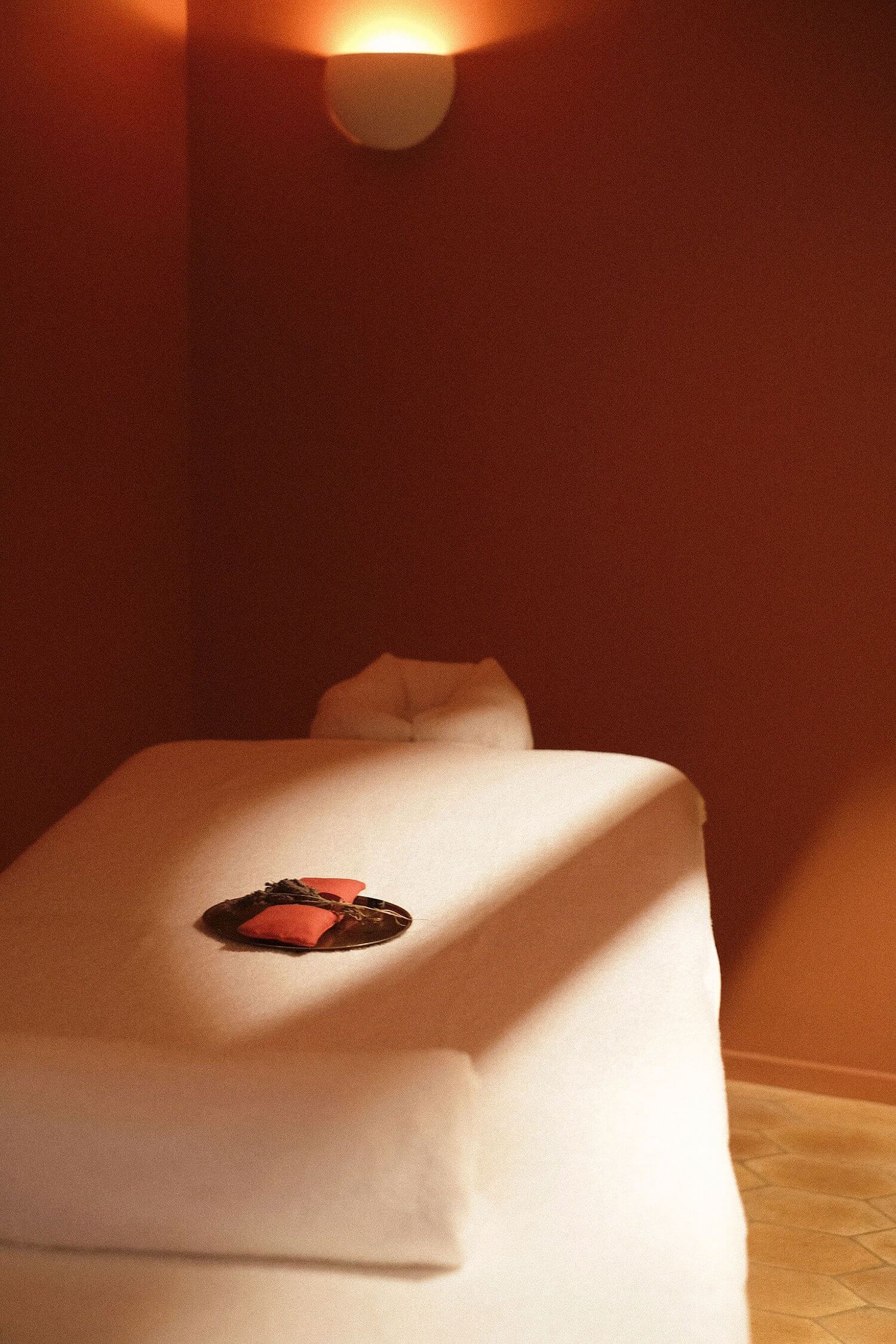 Les Roches Rouges Spa, Europe — Minimalist spa interior with terracotta walls, natural light, white sculptural seating, and red fabric accent detail.
