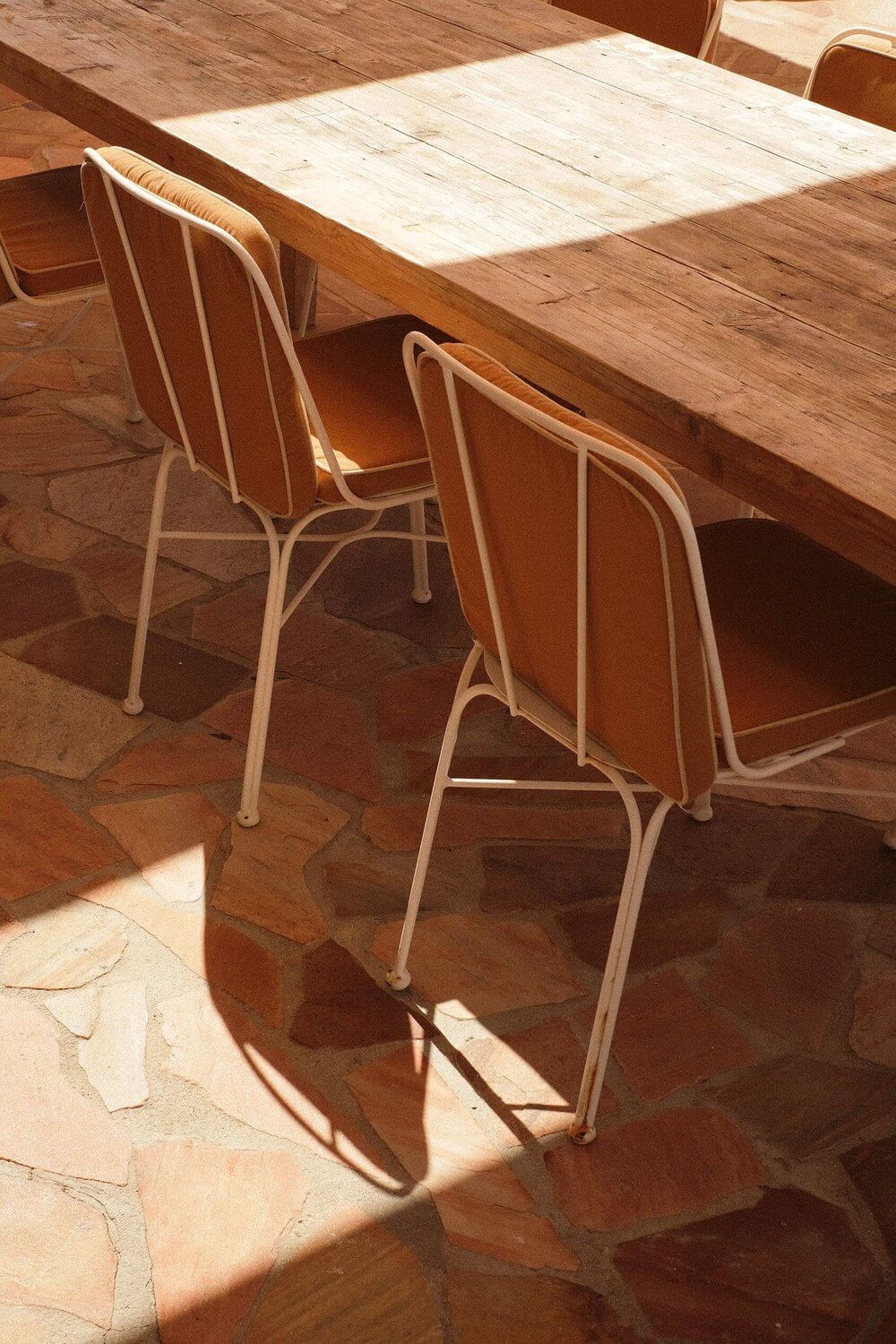 Les Roches Rouges, Europe — Bentwood chairs with woven seats at dining table, sunlit terracotta flooring, minimalist mid-century aesthetic.