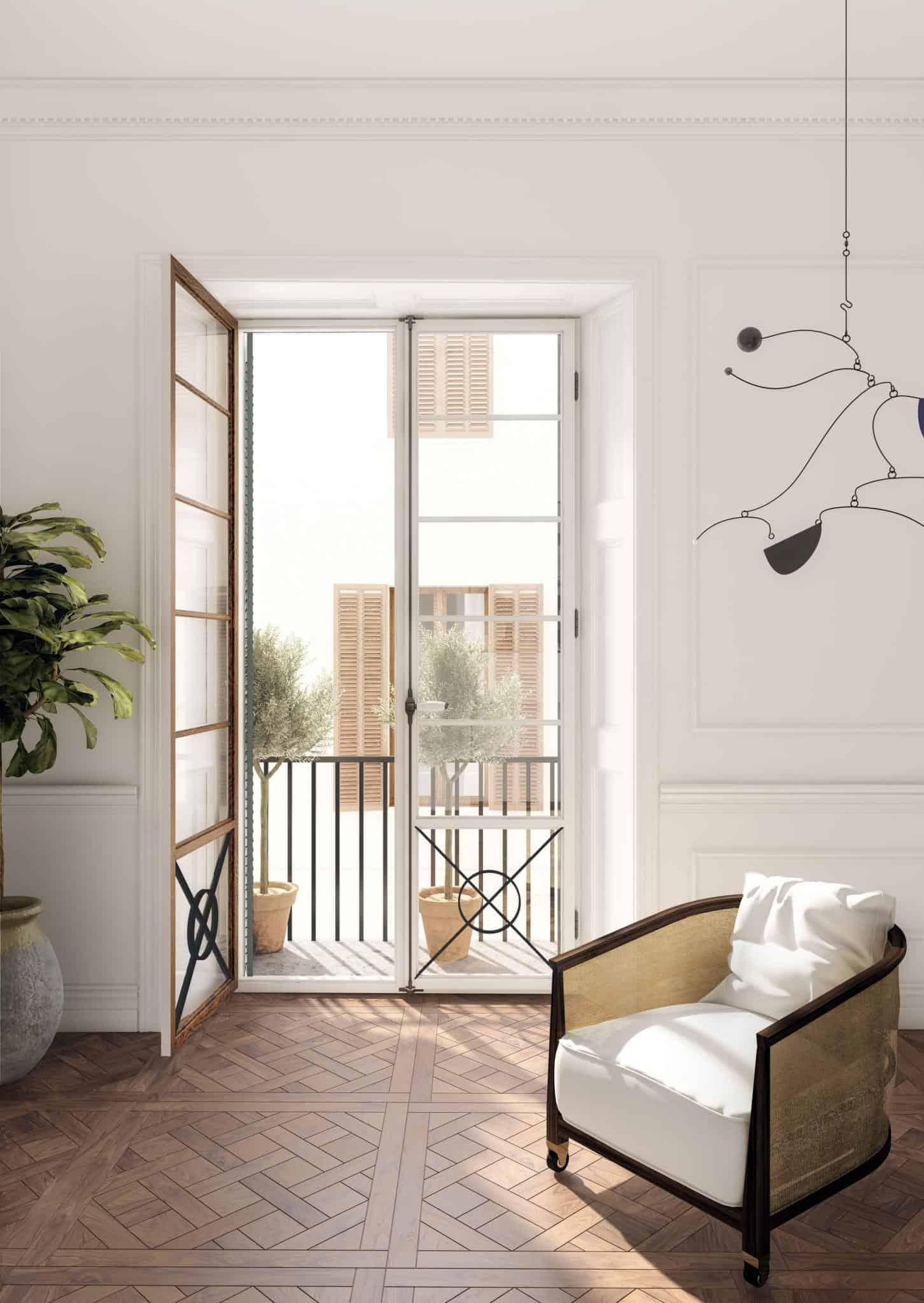 Renaissance Penthouse, Balearic Islands, Spain — Sunlit bedroom with open French doors to balcony, herringbone wood floors, modern mobile sculpture, upholstered chair, Mediterranean shutters and olive trees visible beyond.