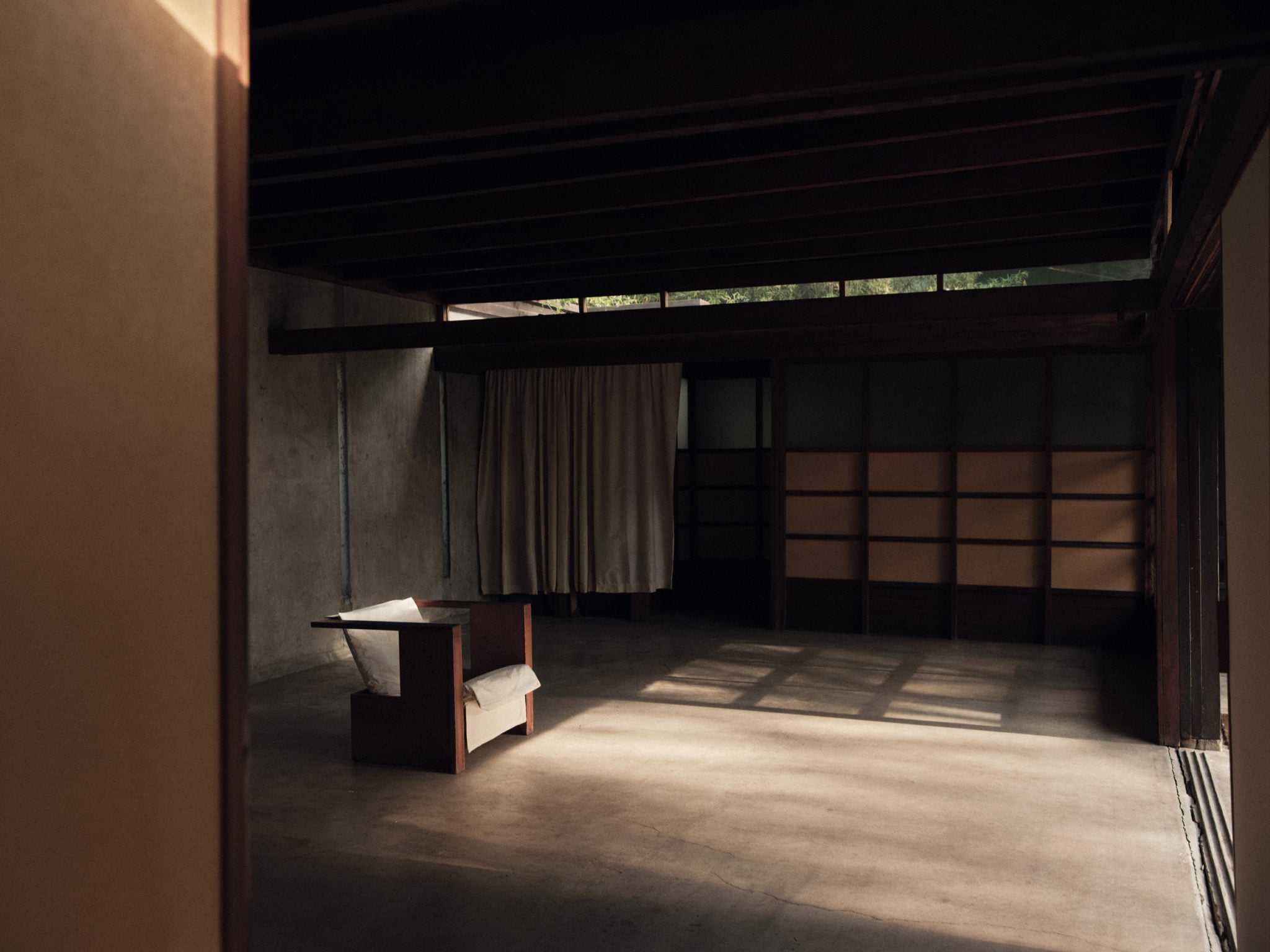 Schindler House, North America — Minimalist concrete studio with clerestory windows, wooden screen panels, and dramatic natural light casting geometric shadows across polished floor.