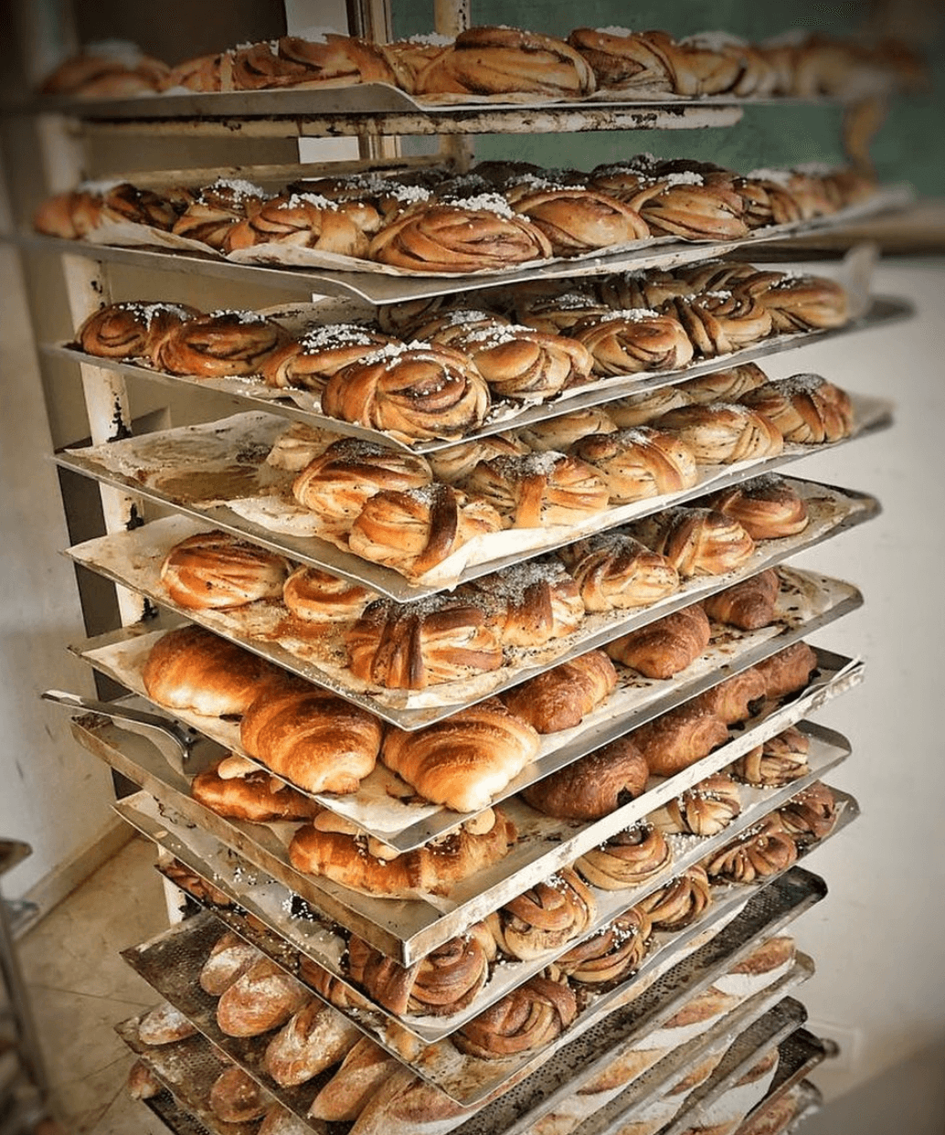 Fika Farina, Balearic Islands, Spain — Stacked baking trays of freshly baked pastries and cinnamon rolls cooling in artisan bakery kitchen.