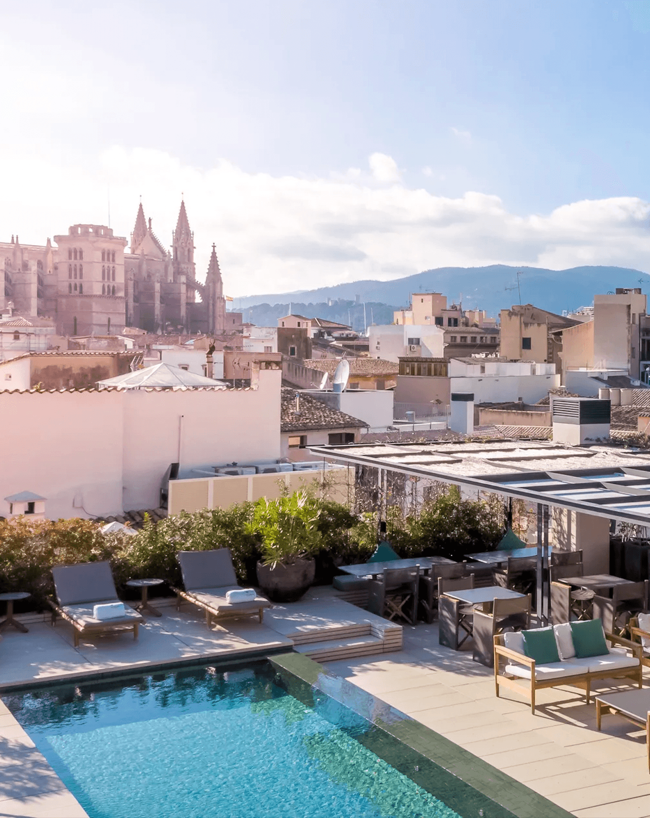 Sant Francesc Hotel Singular, Balearic Islands, Spain — Rooftop pool with loungers overlooking Gothic cathedral and Mediterranean architecture in warm sunlight.