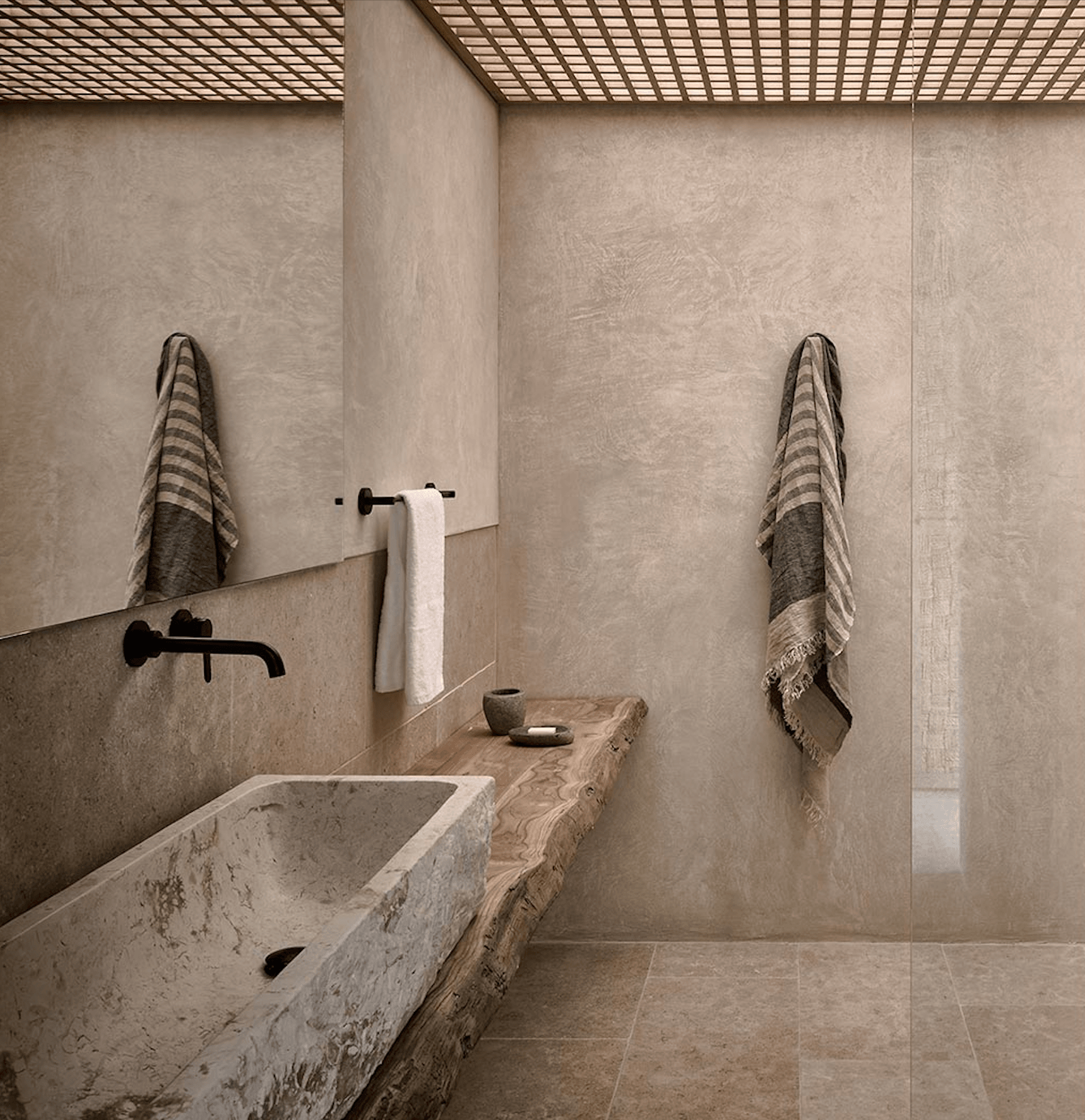 Olea All Suite Hotel, Europe — Minimalist bathroom with travertine sink, wooden counter, black fixtures, striped linen towels, lattice ceiling, neutral plaster walls.