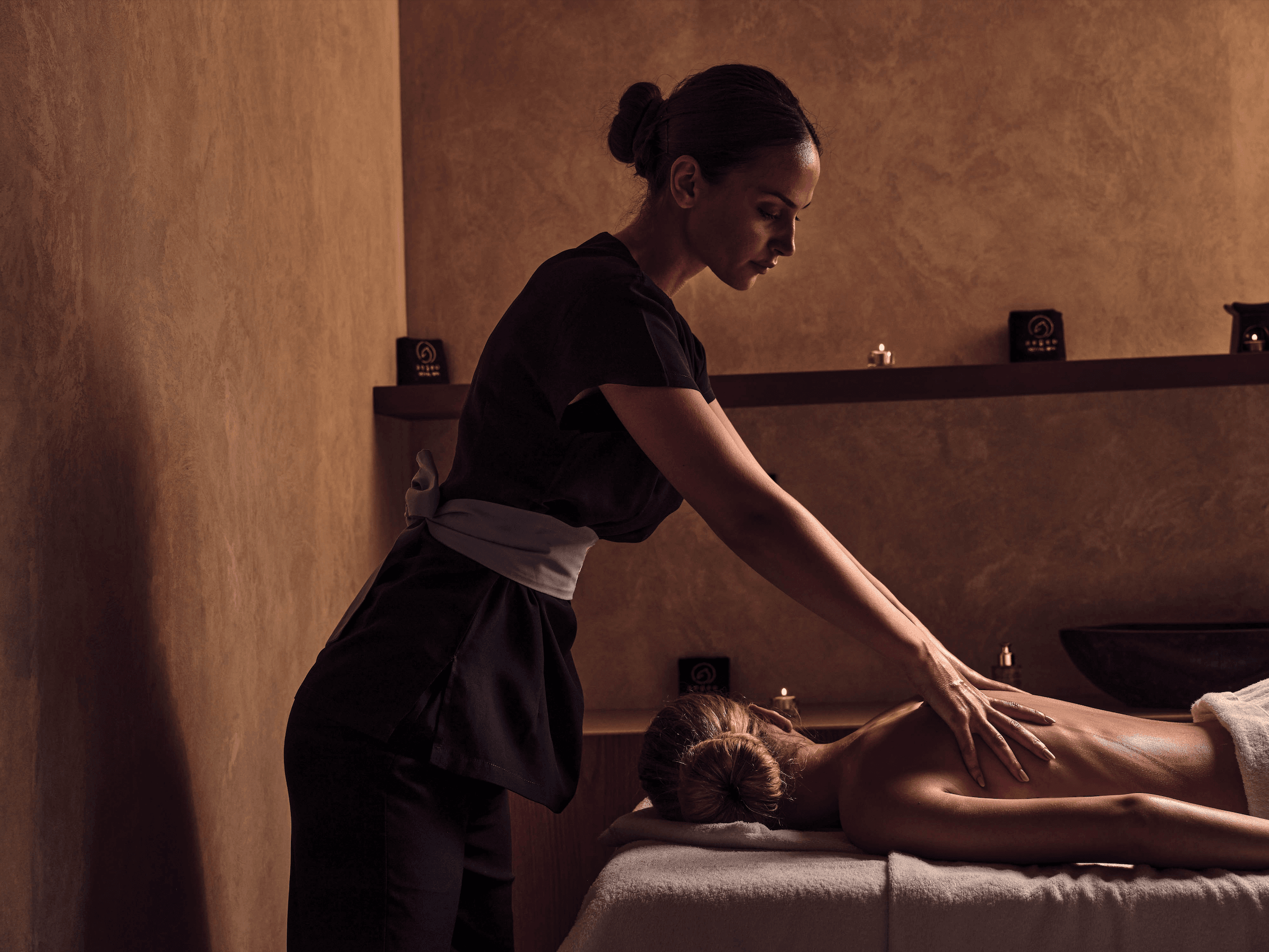 Royal Spa, Europe — Therapist performing back massage in candlelit wellness room with warm ambient lighting and neutral tones.