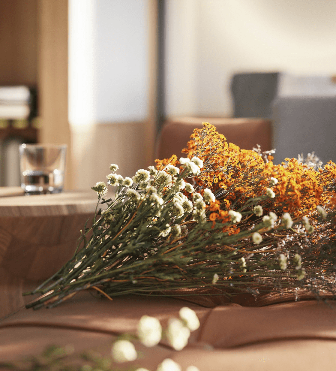 The Cōmodo — Dried botanicals and goldenrod arranged on wooden surface with warm natural light, luxury hotel interior styling.