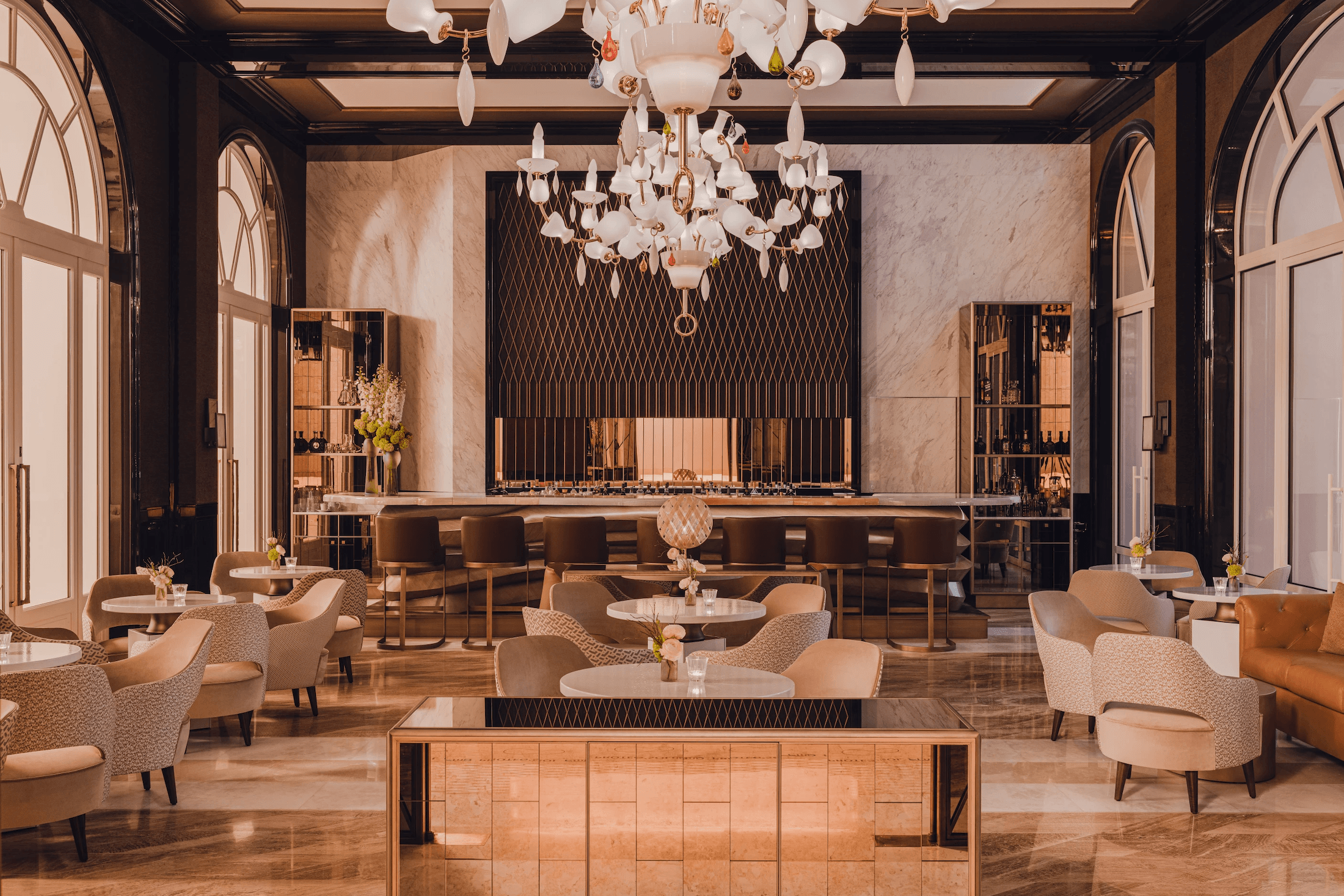 Bar°58, Europe — Luxury lounge with cream leather chairs, marble walls, brass fixtures, and ornate white chandelier above polished wood bar.