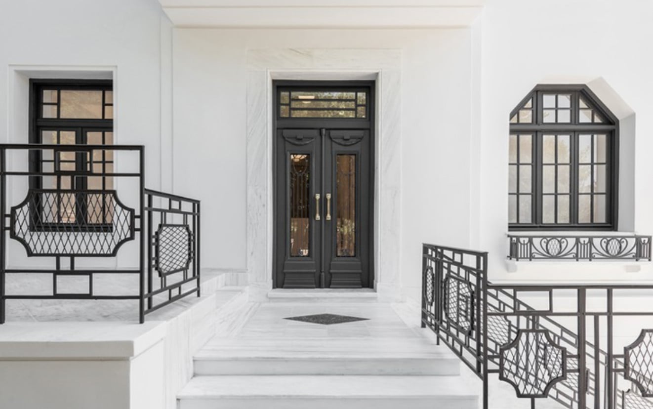 Gagosian Gallery, Europe — Neoclassical marble entrance with black-framed glass doors, geometric railings, and symmetrical windows in minimalist white interior.